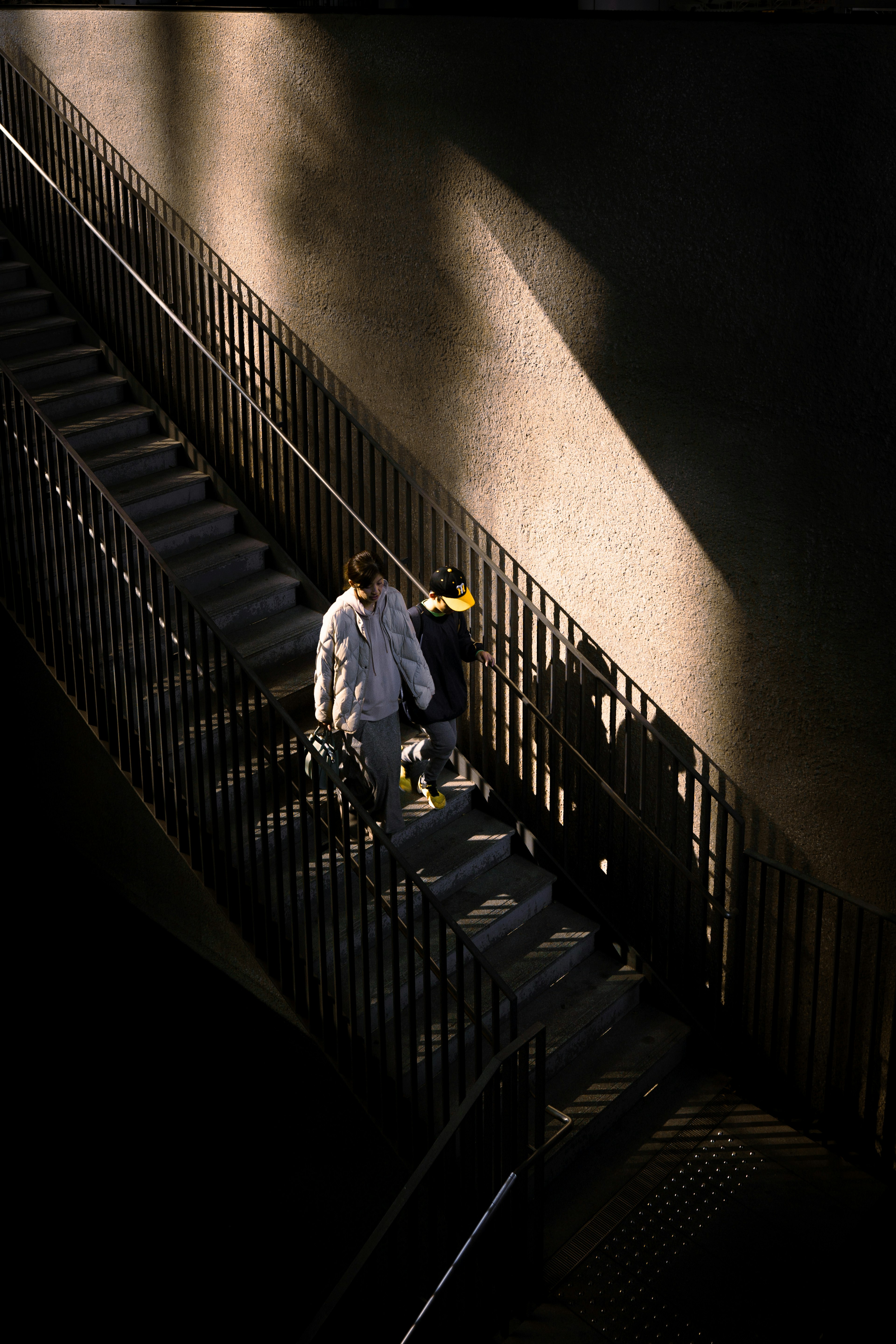 Dos personas subiendo una escalera oscura con sombras llamativas