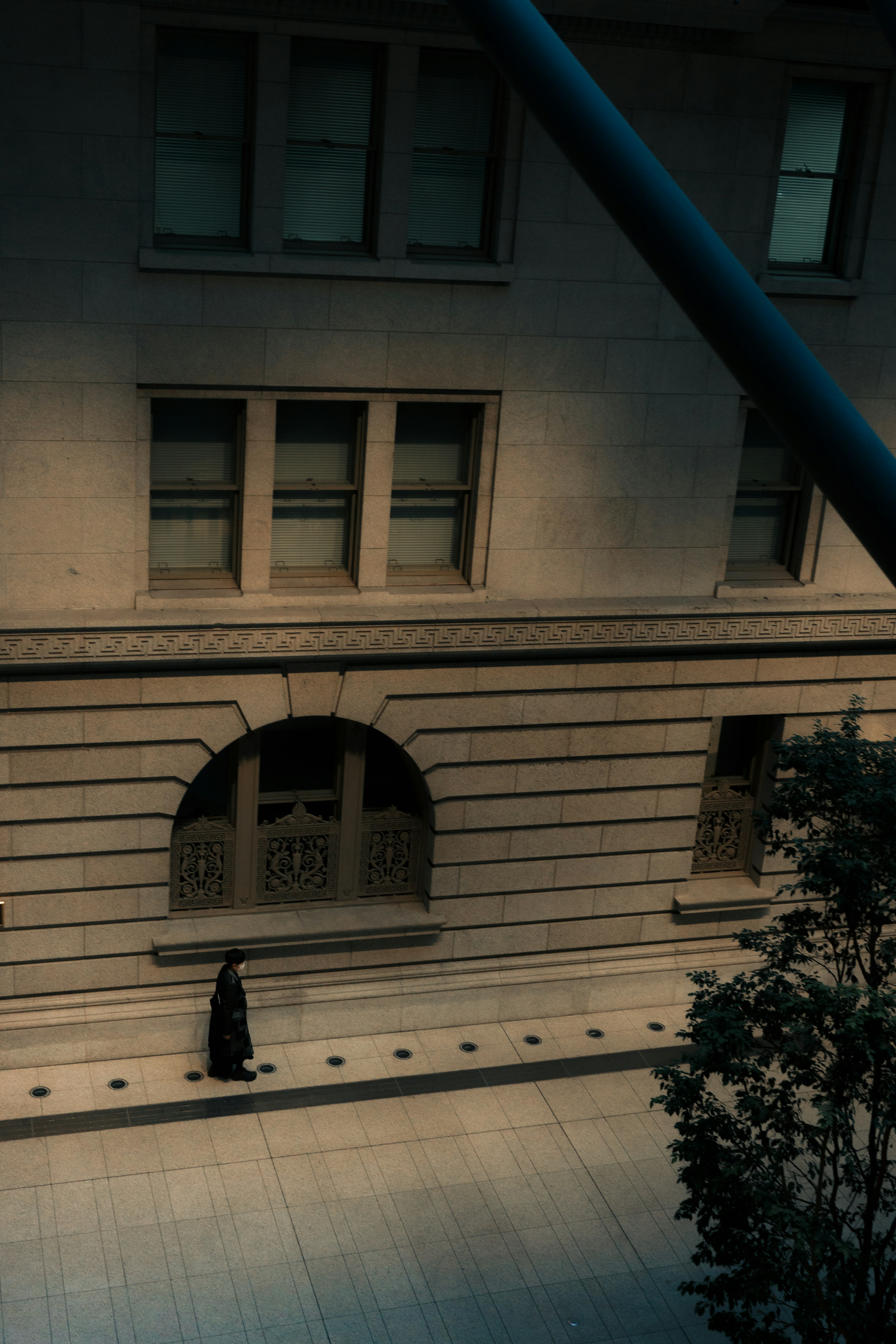 A person in black walking down a dimly lit street beside an old building