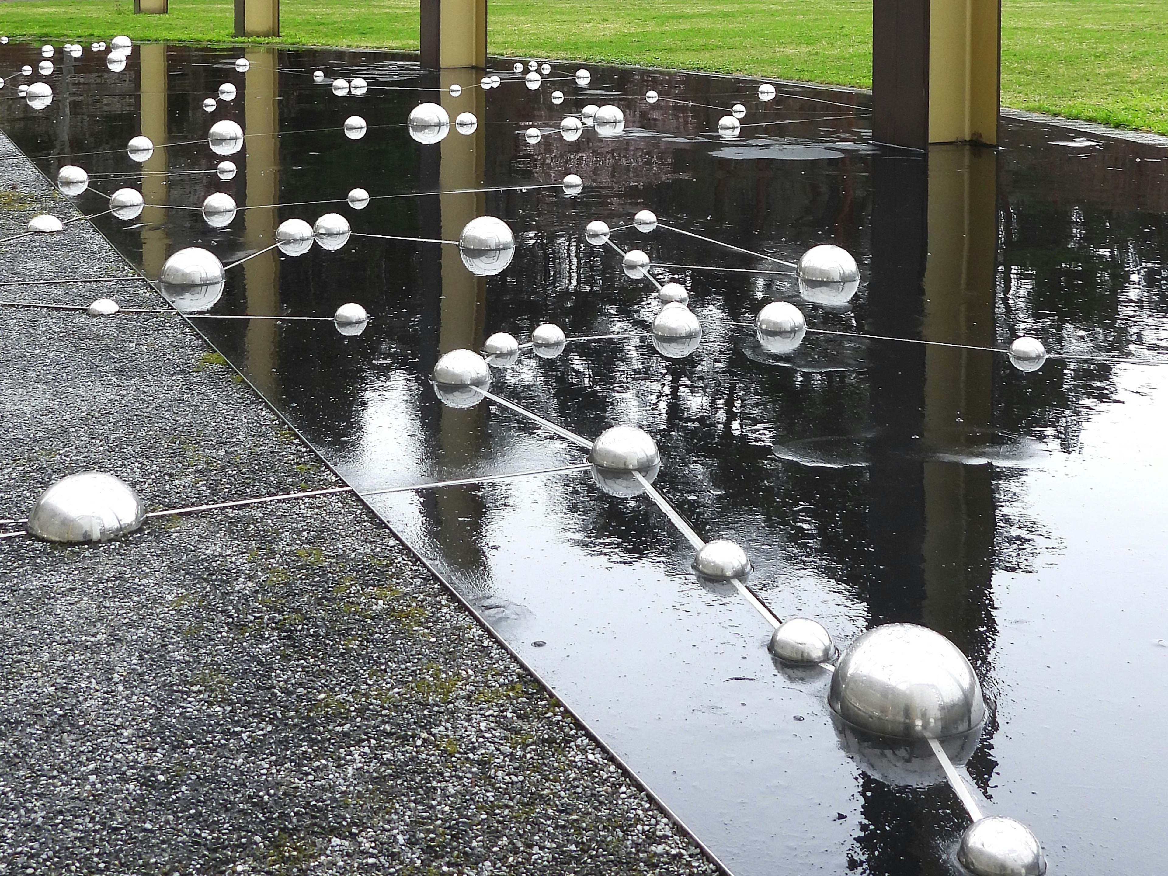 Instalación artística con esferas plateadas flotando en la superficie del agua