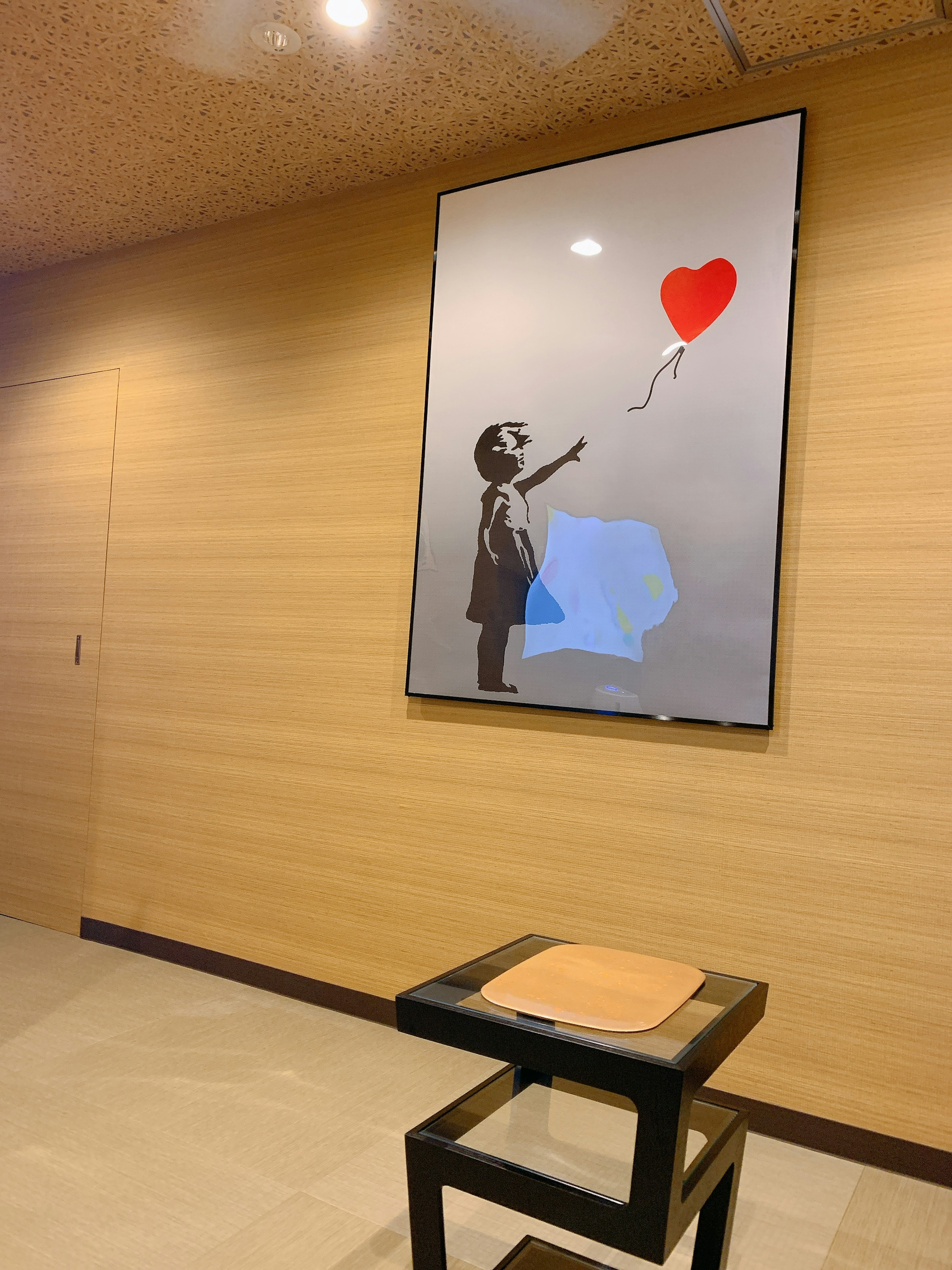 A Banksy-style artwork on the wall featuring a child holding a red heart balloon