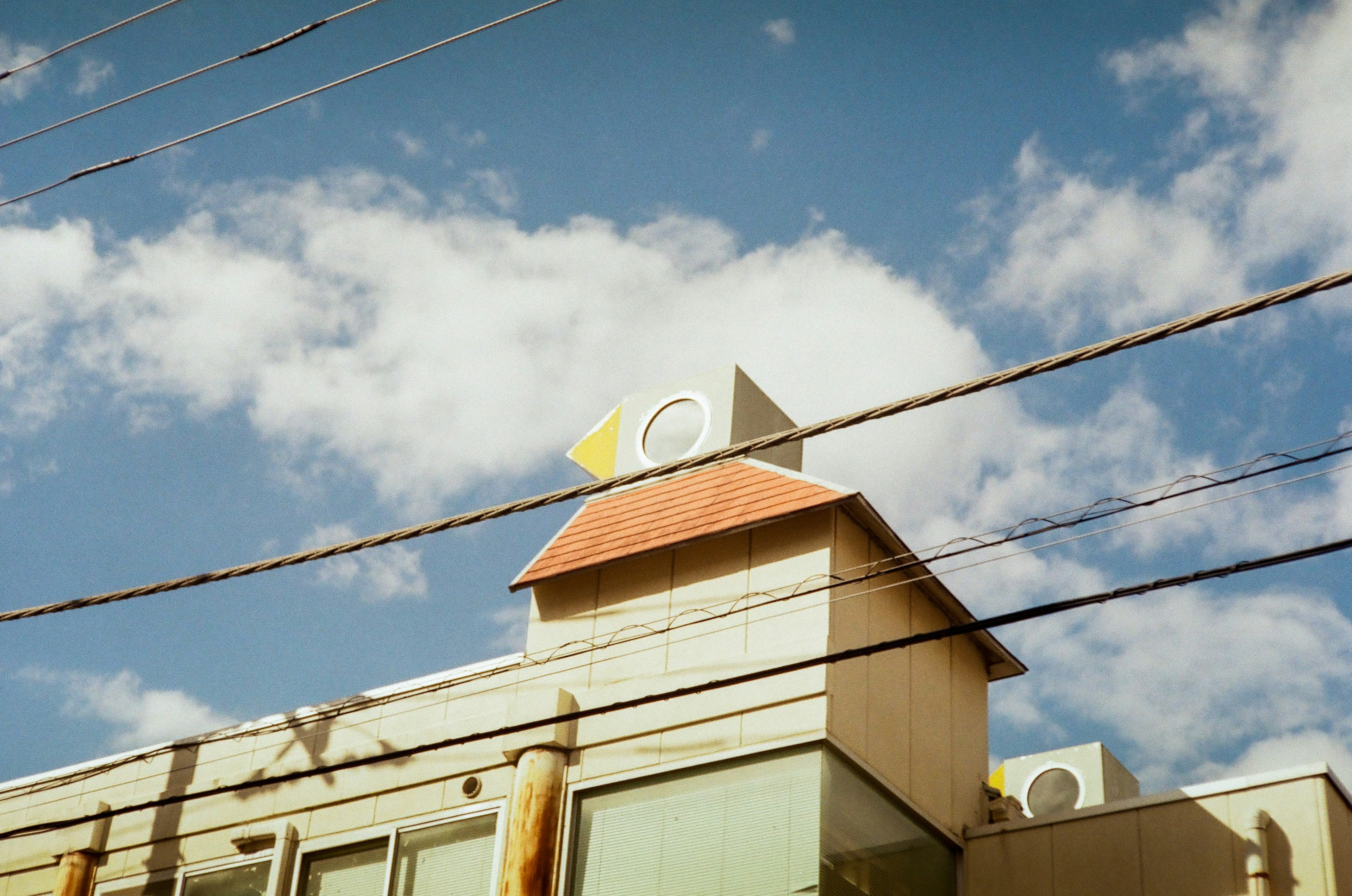 Building rooftop featuring a triangular and circular design under a blue sky