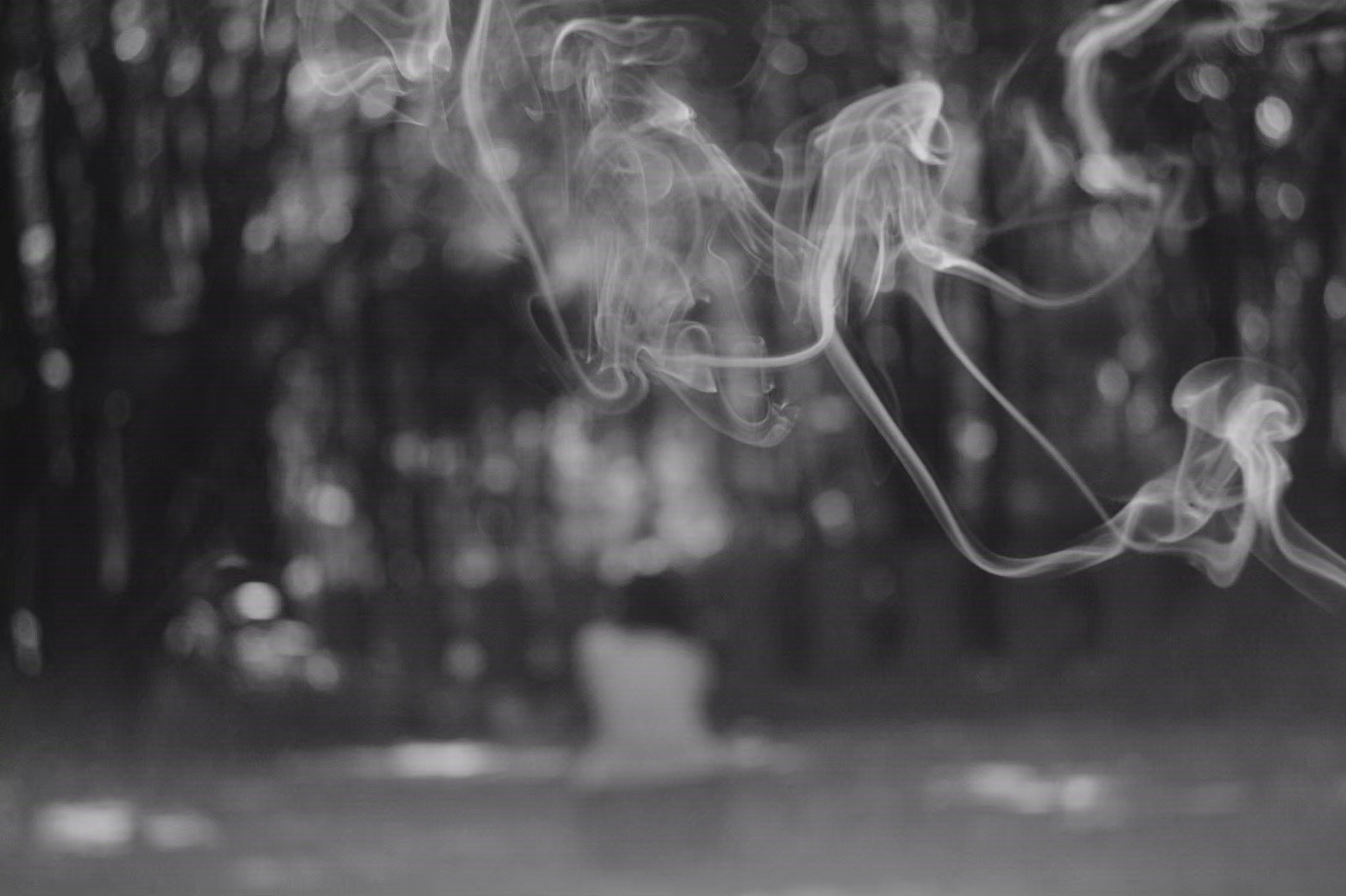 Silhouette of a person sitting in a forest with drifting smoke