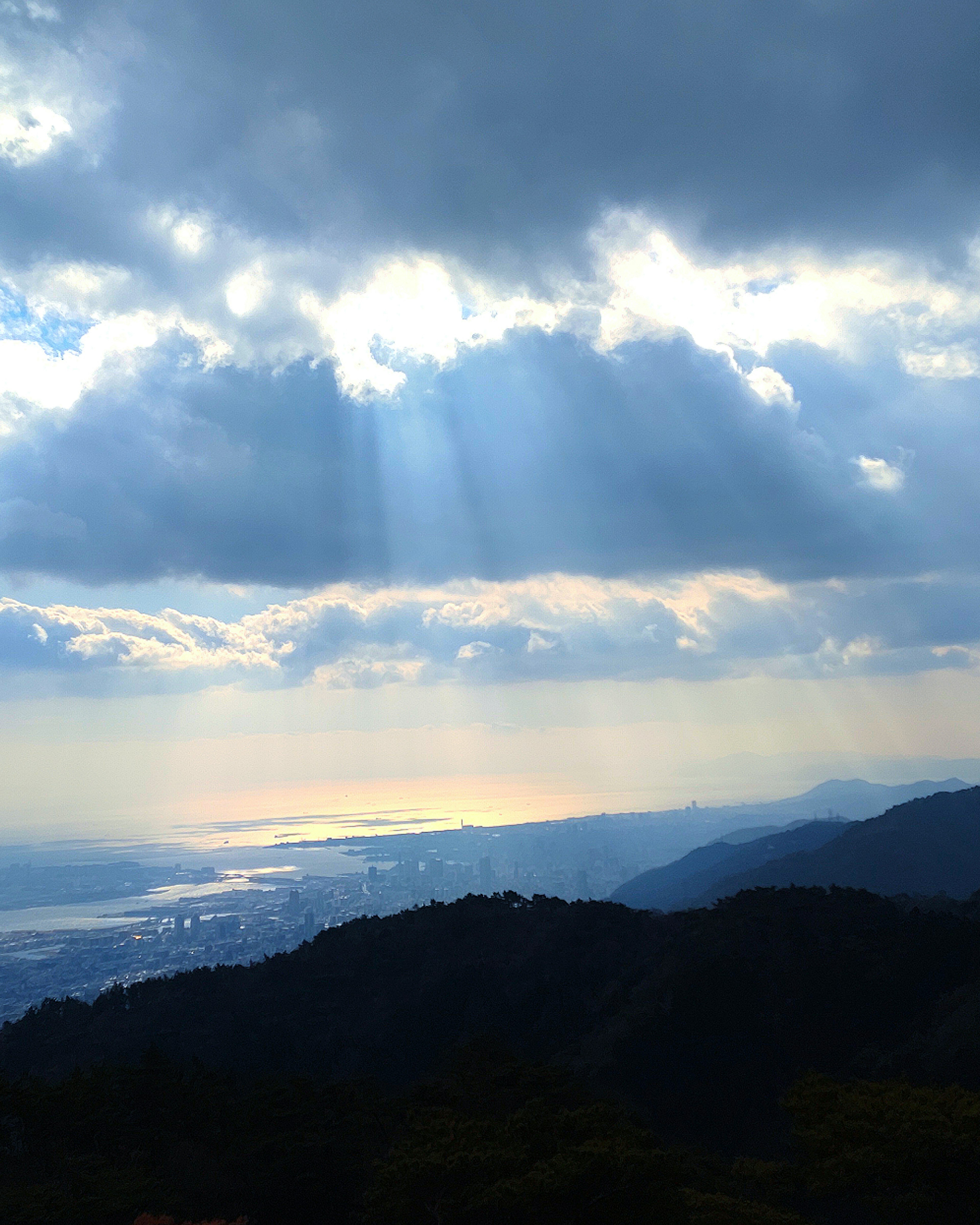 Sunlight breaking through clouds over mountains and a body of water