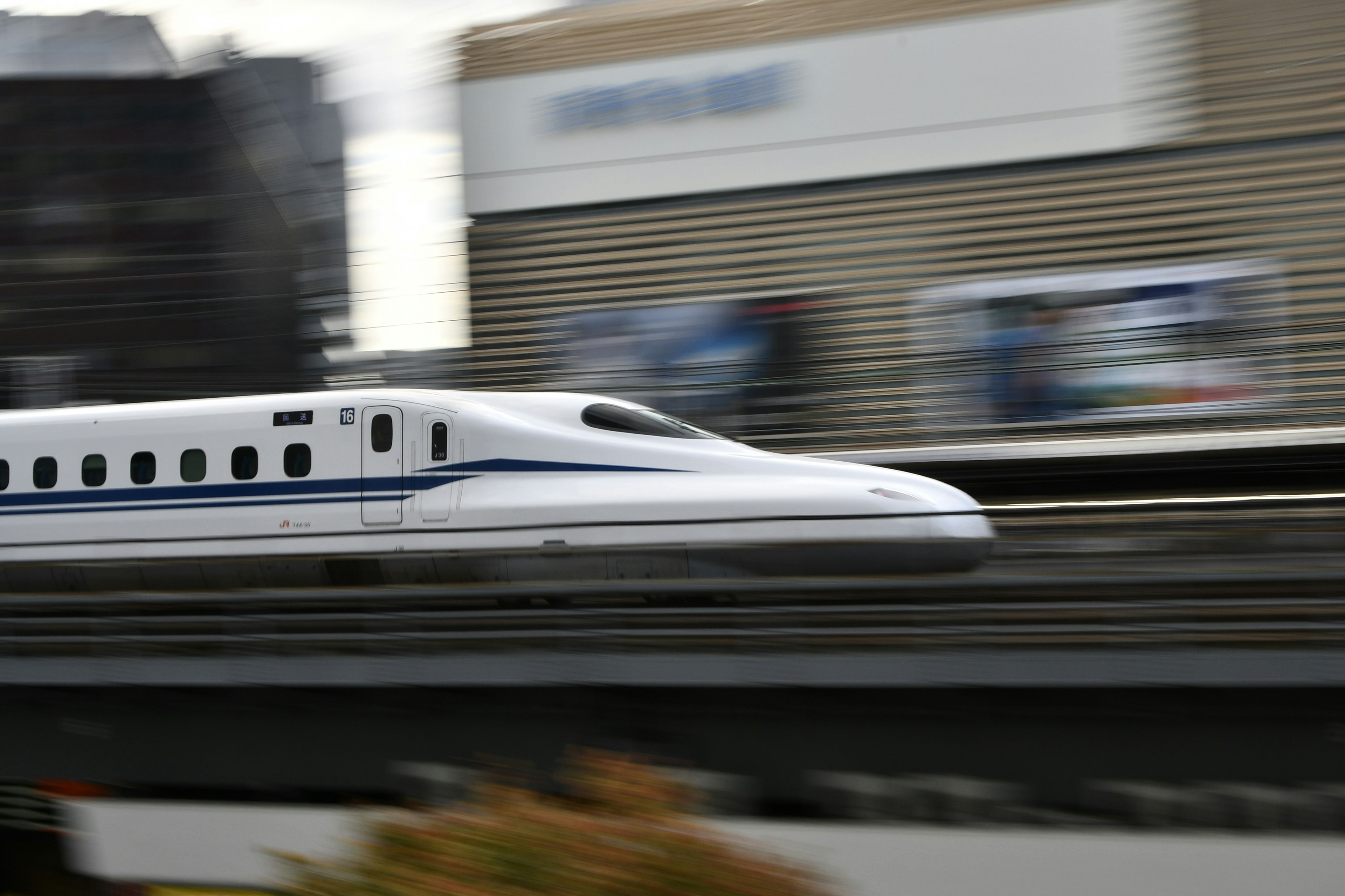 Immagine di un treno Shinkansen che corre veloce su un binario