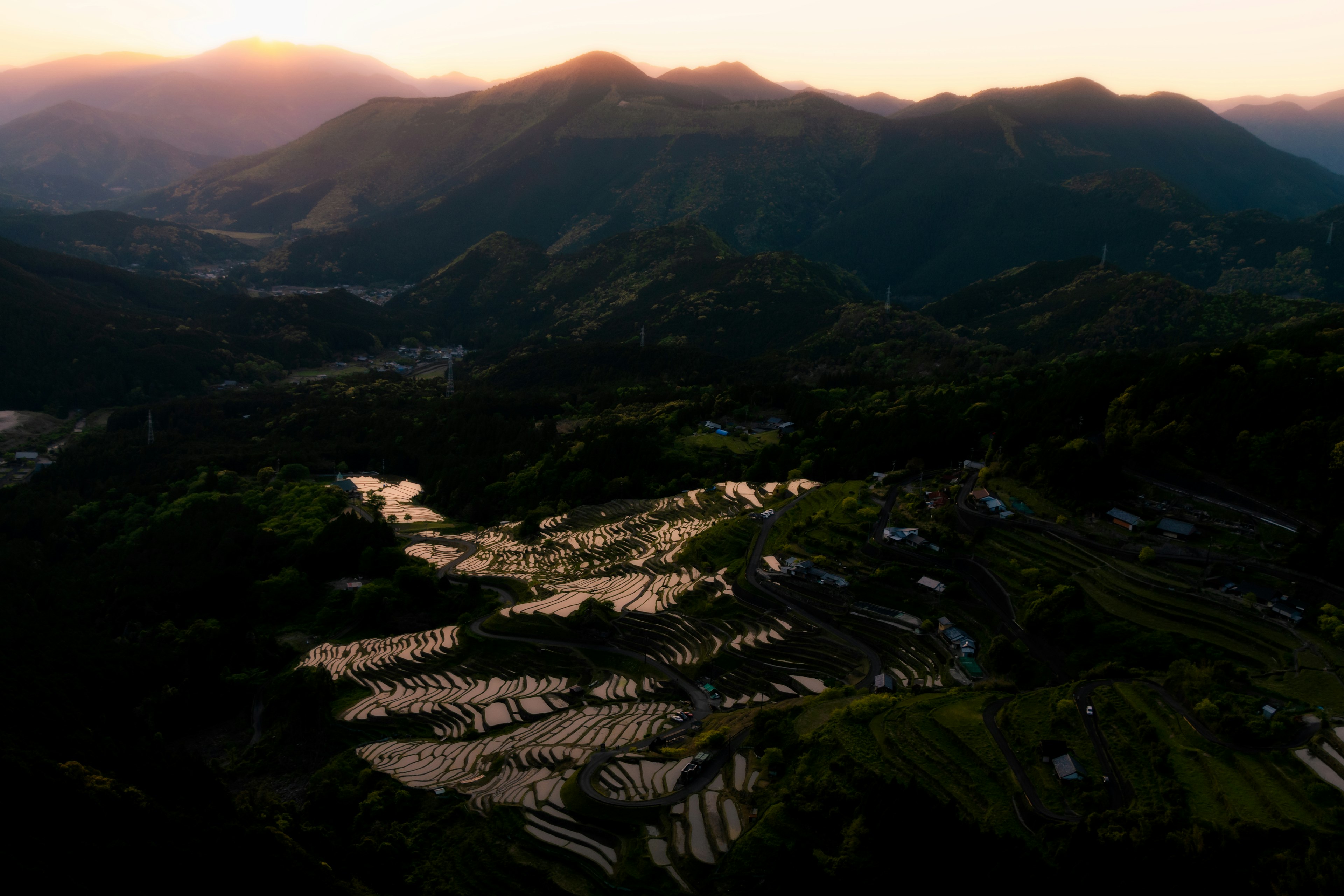 山の間に広がる棚田と夕日の美しい風景