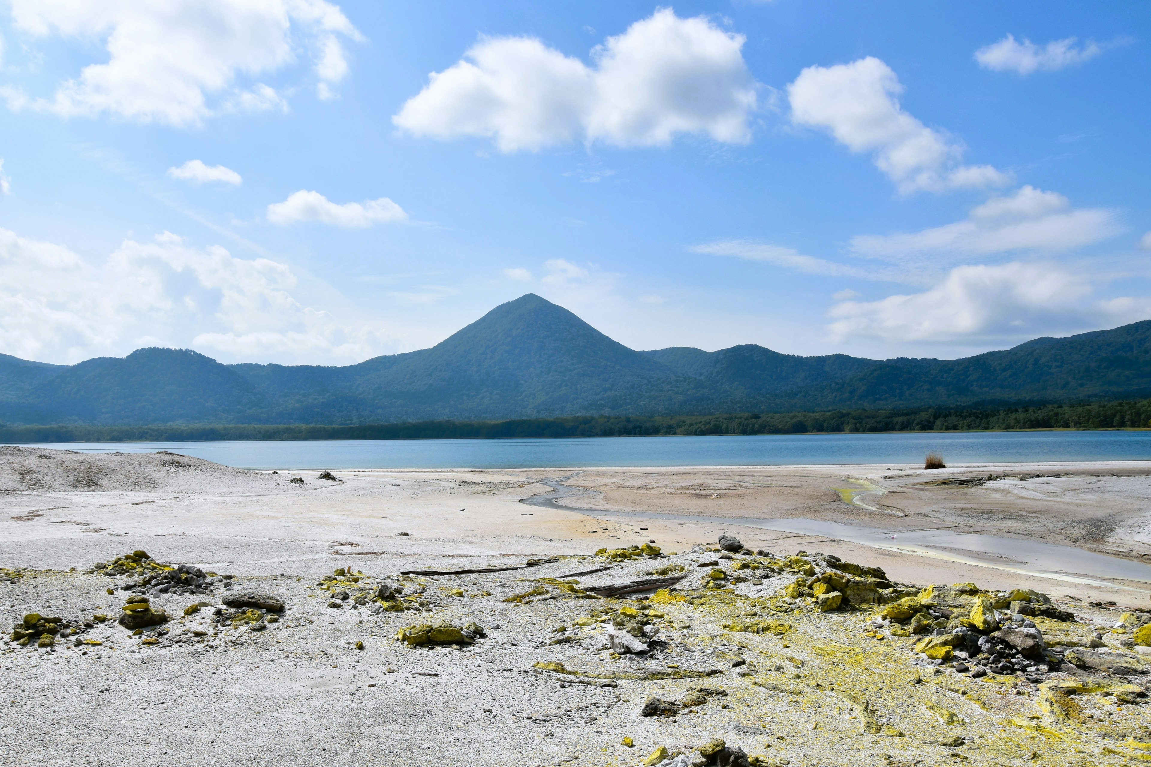 青い空と白い雲の下に広がる美しい湖の風景と山