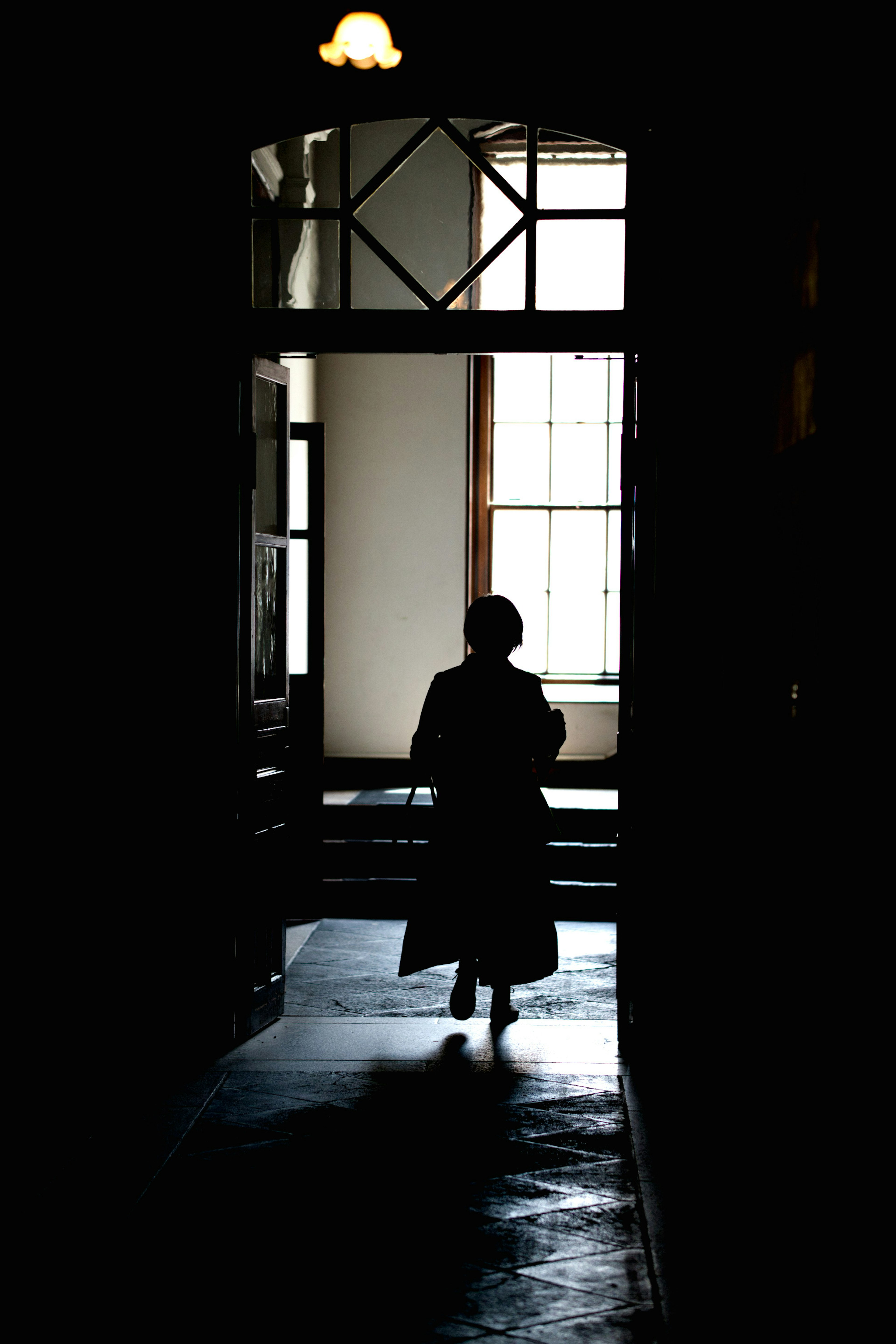 Silhouette di una persona che esce da un corridoio poco illuminato