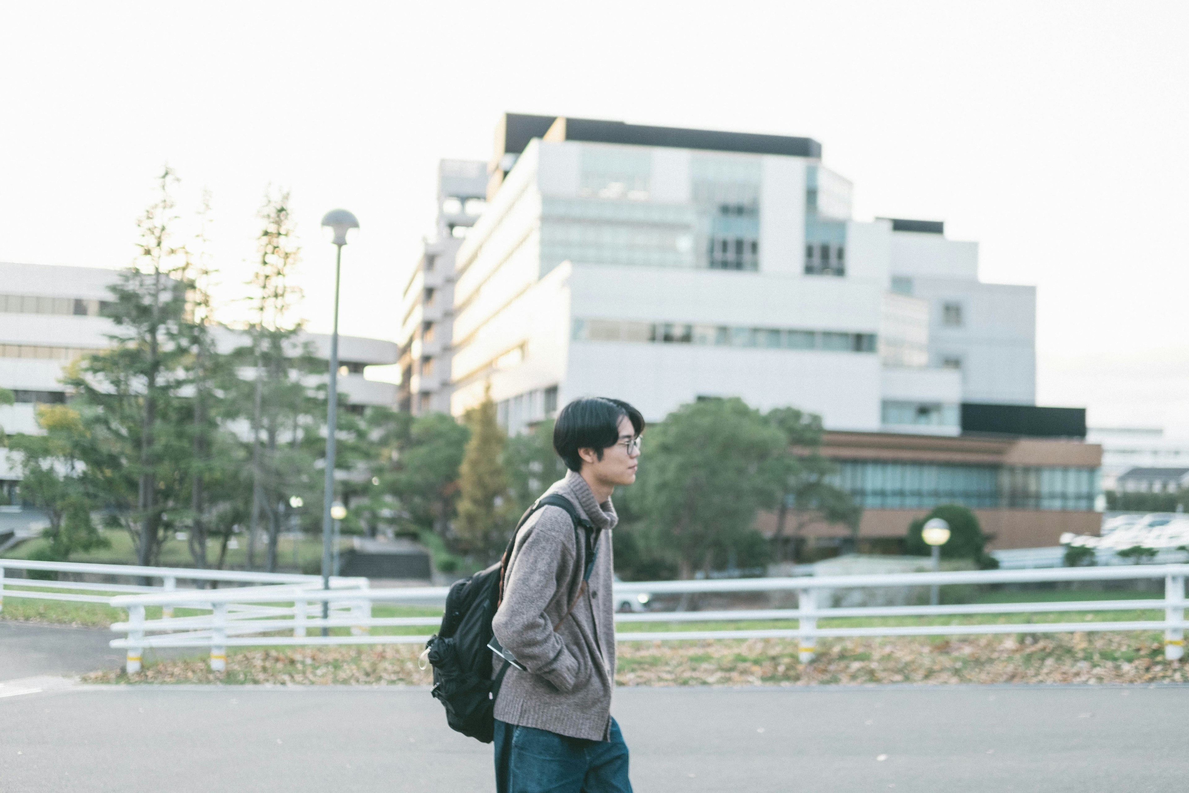 公園を歩く若い男性と現代的な建物