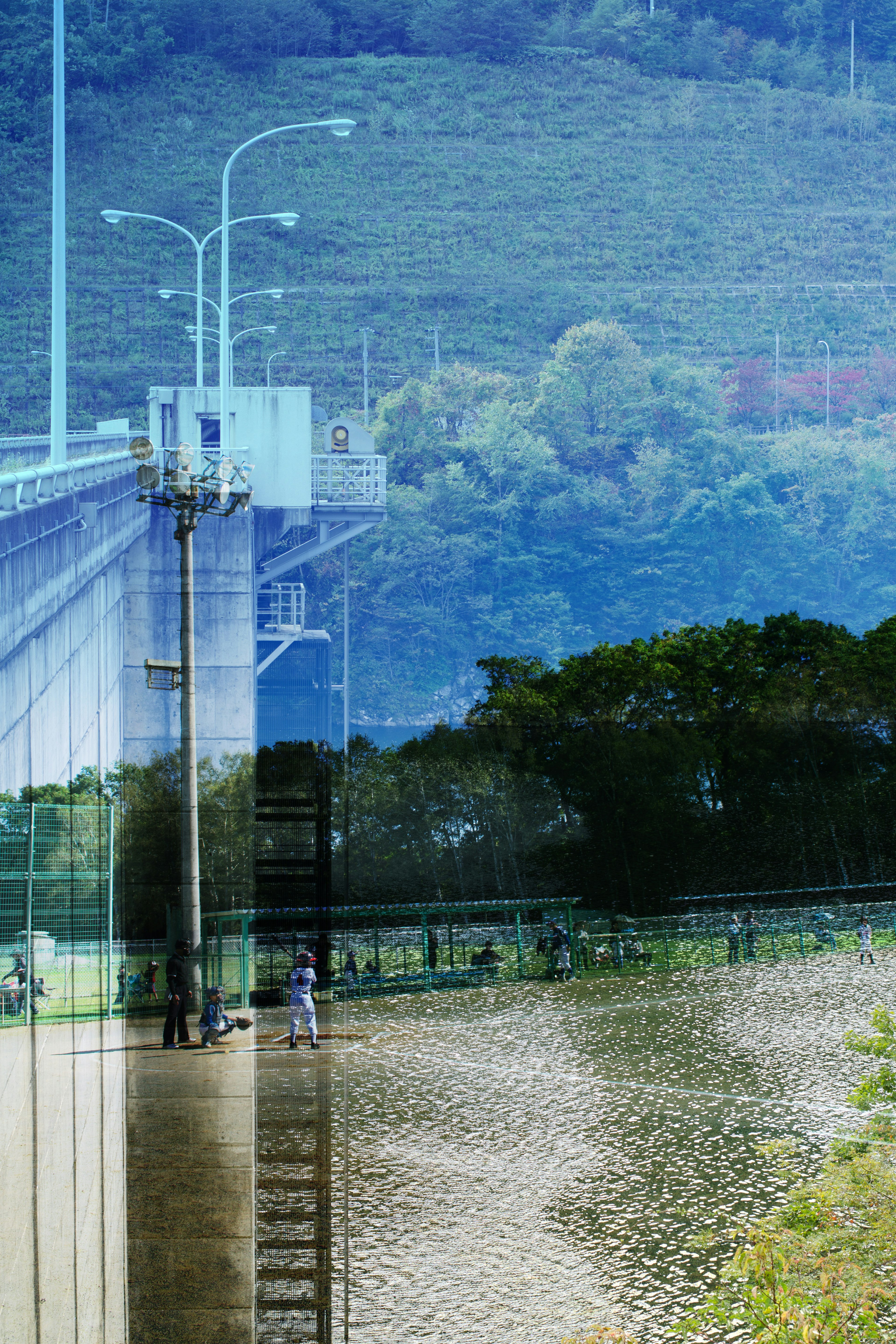 A reflective view of a river with a bridge and surrounding greenery