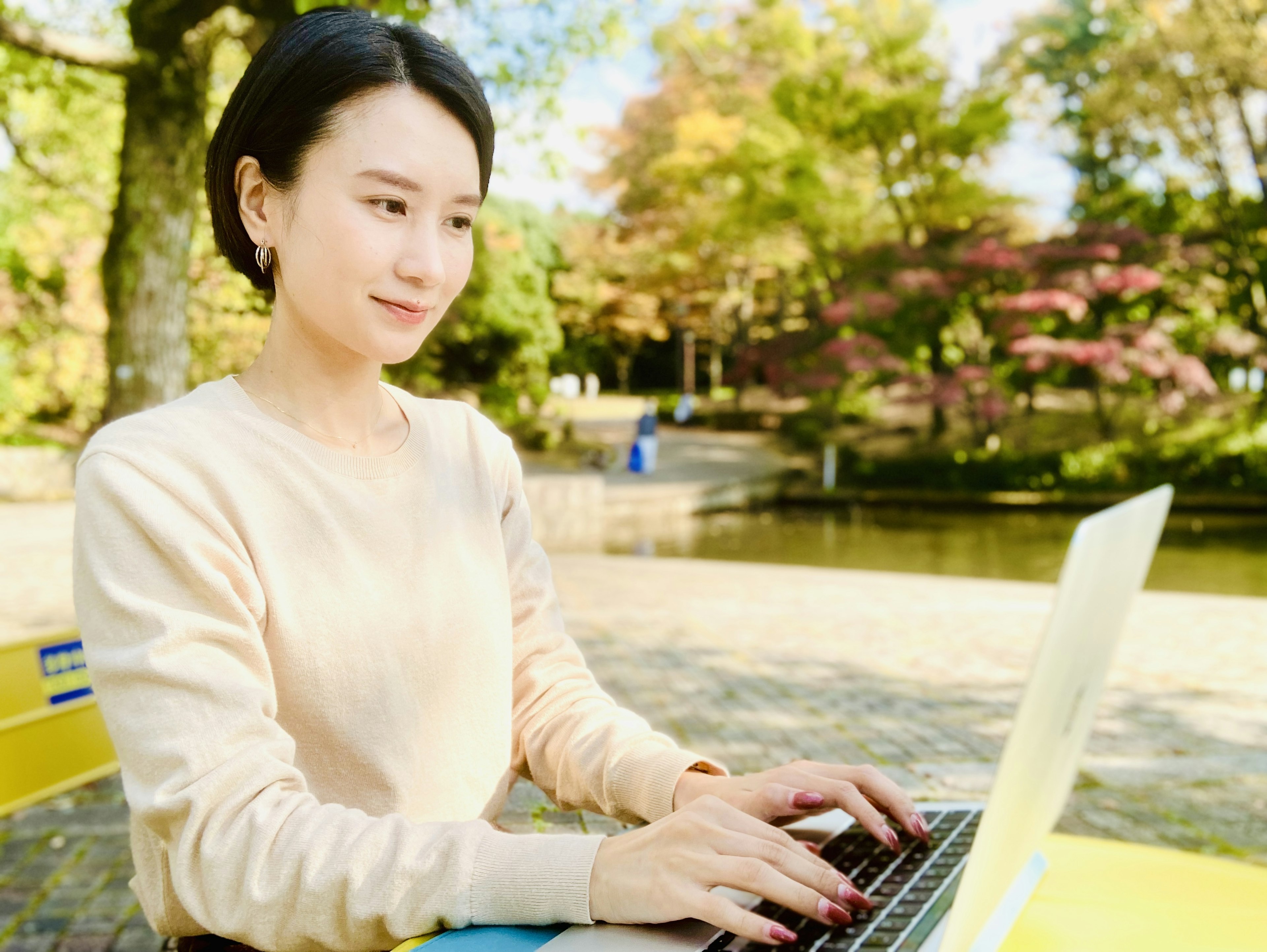 공원에서 노트북을 사용하는 여성 푸르른 배경과 가을 색상