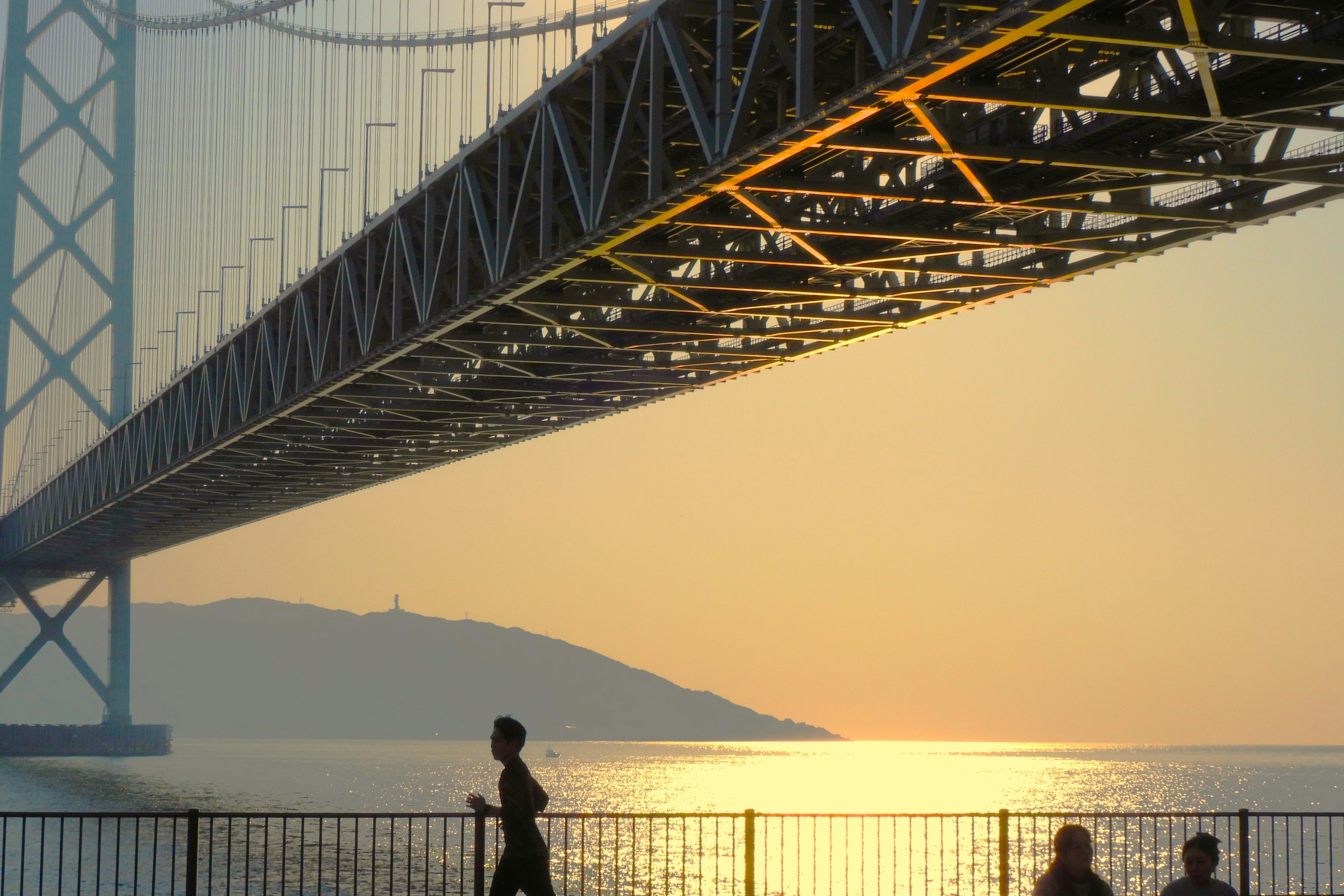 Persone che camminano sotto un ponte al tramonto