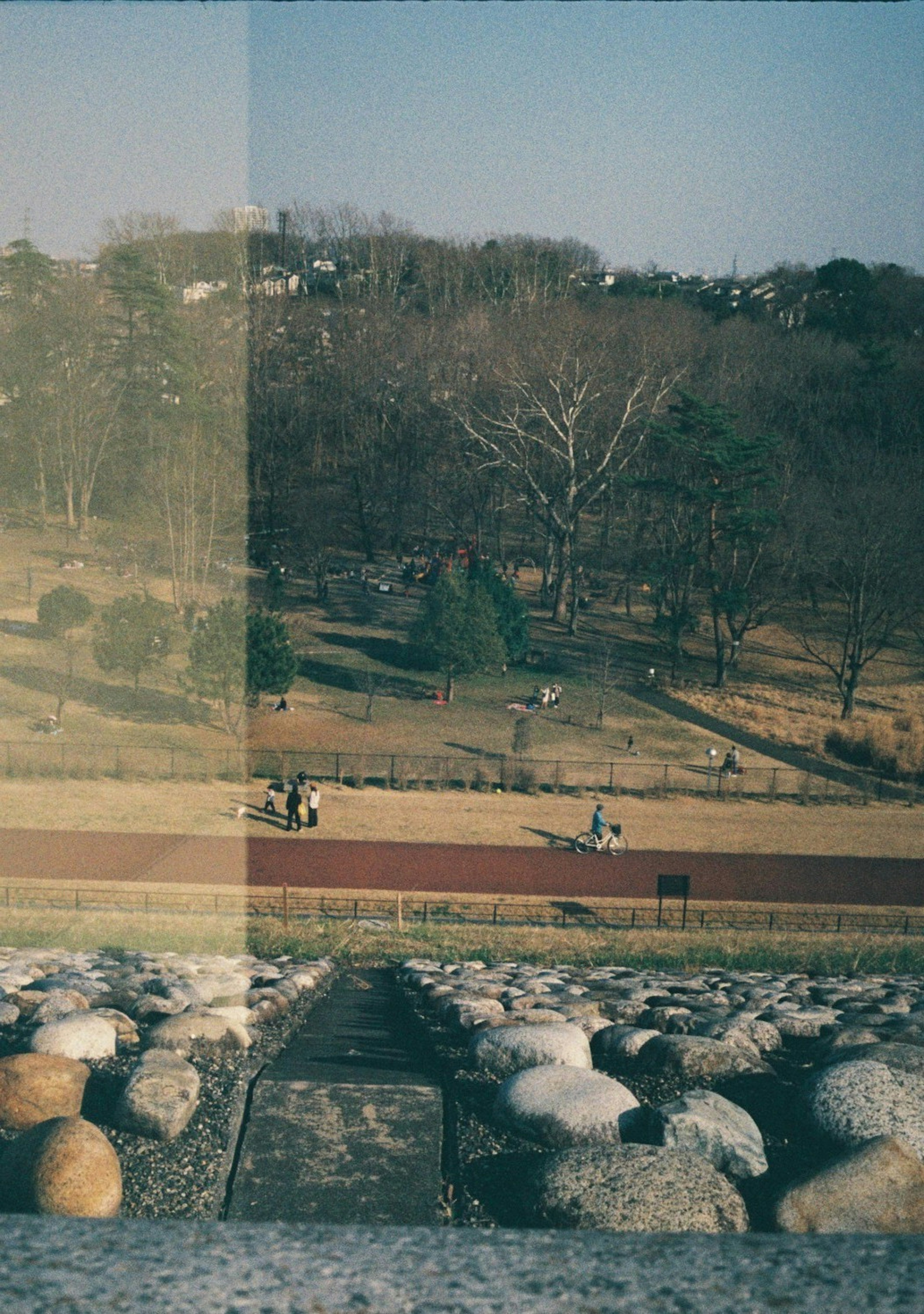 Park landscape with stone steps, people running on track, visible trees