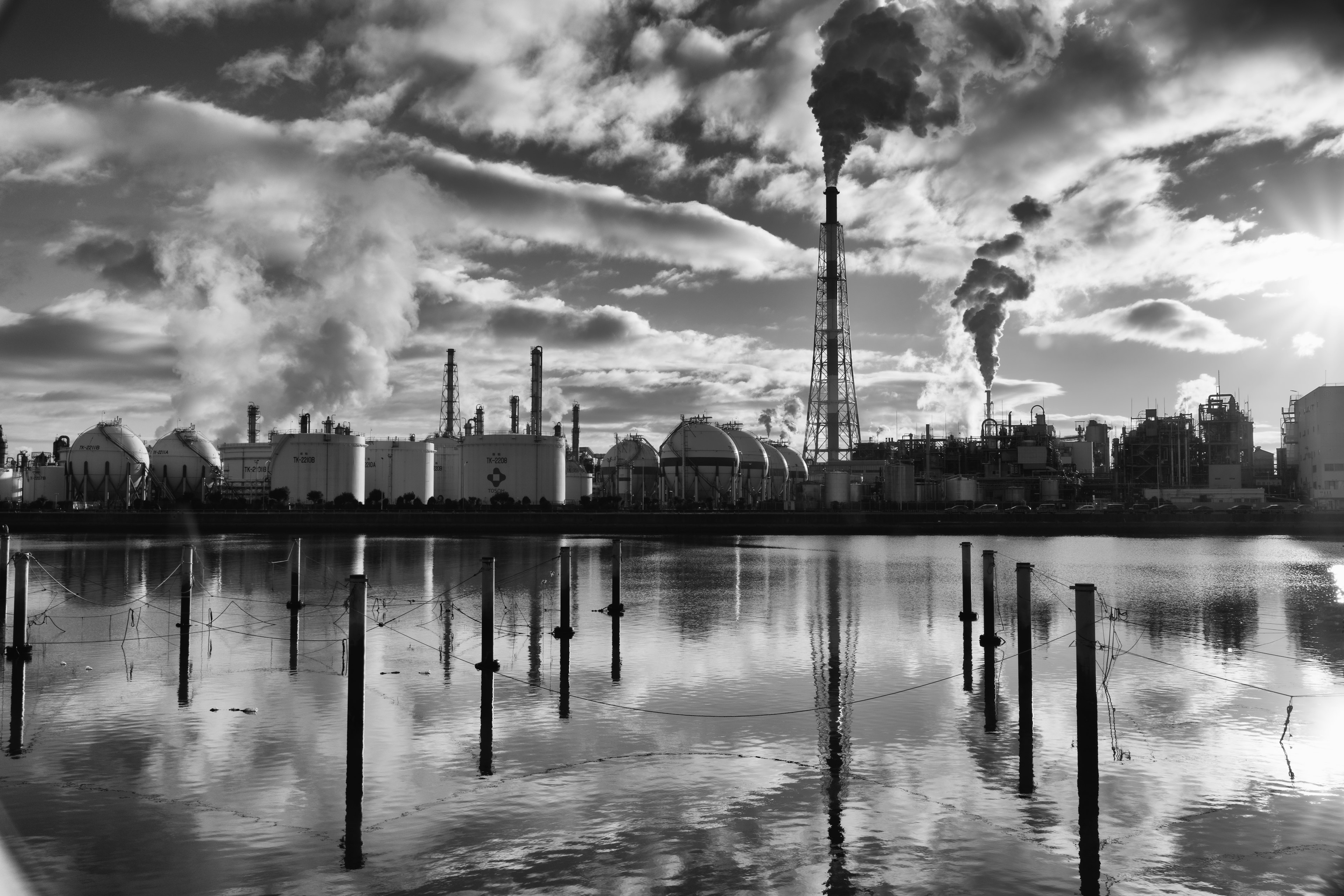 Industrial landscape with smokestacks and clouds reflected on water surface in black and white