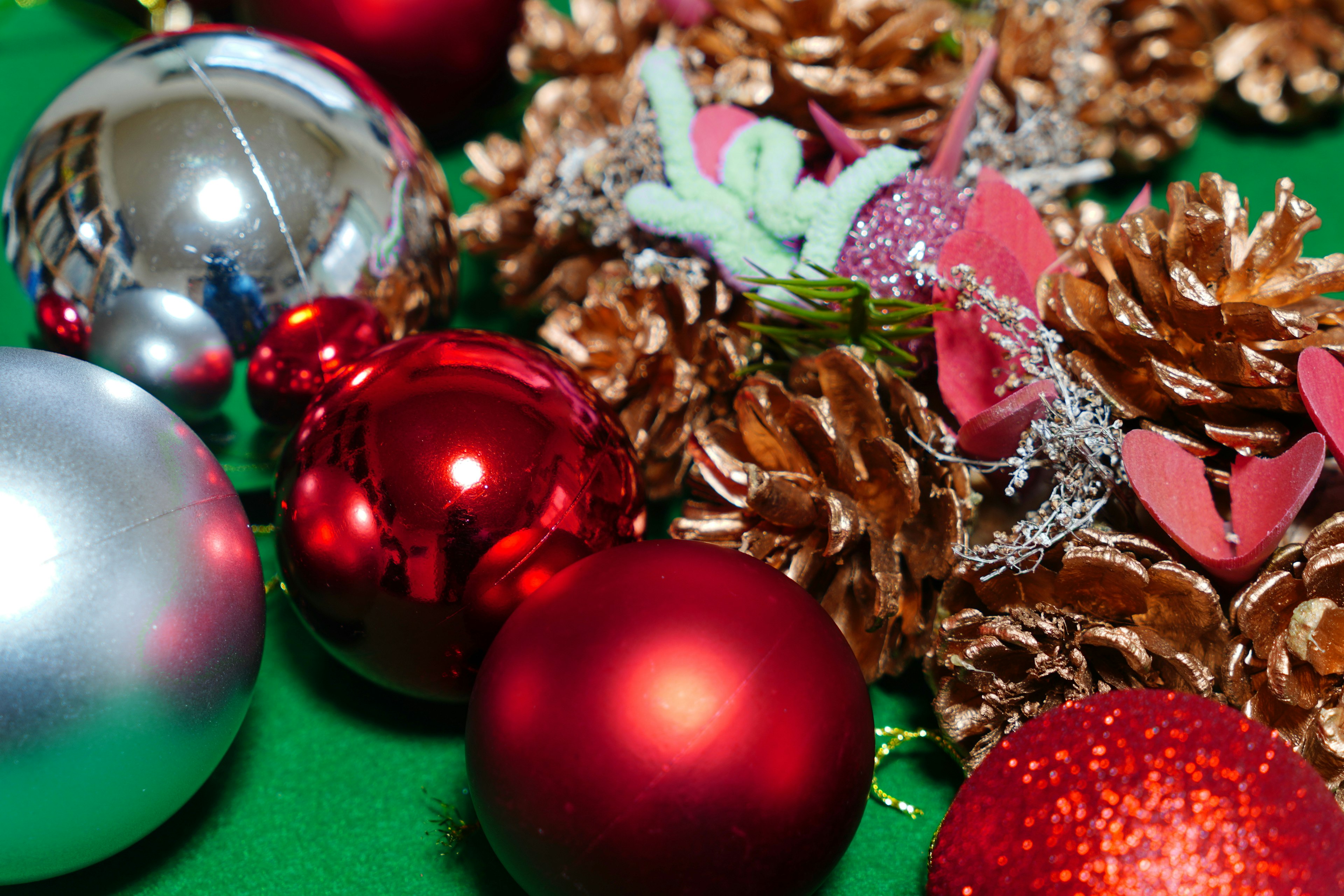 Christmas ornaments and pine cones arranged on a green background