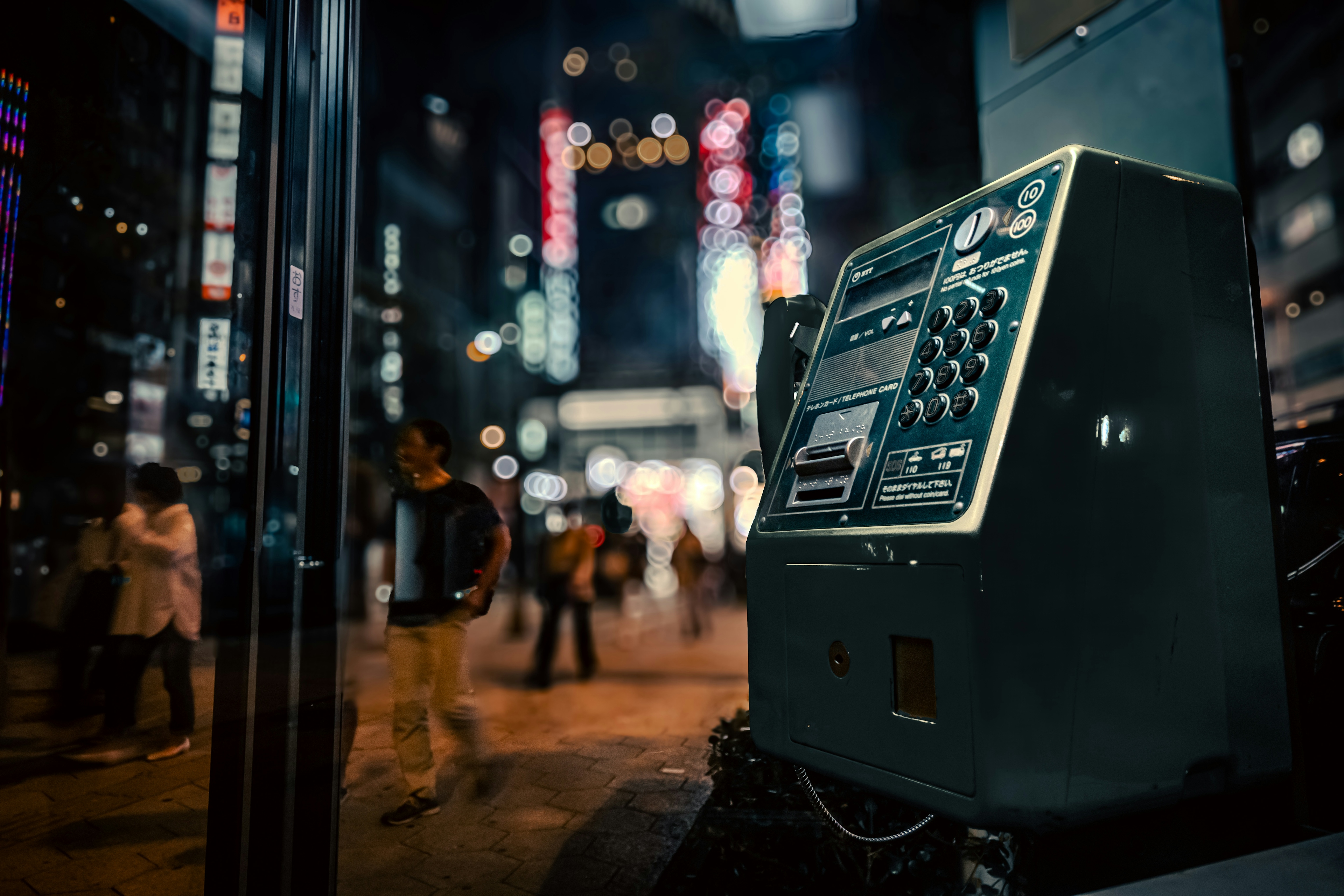 Foto di un vecchio telefono pubblico in una città vivace di notte