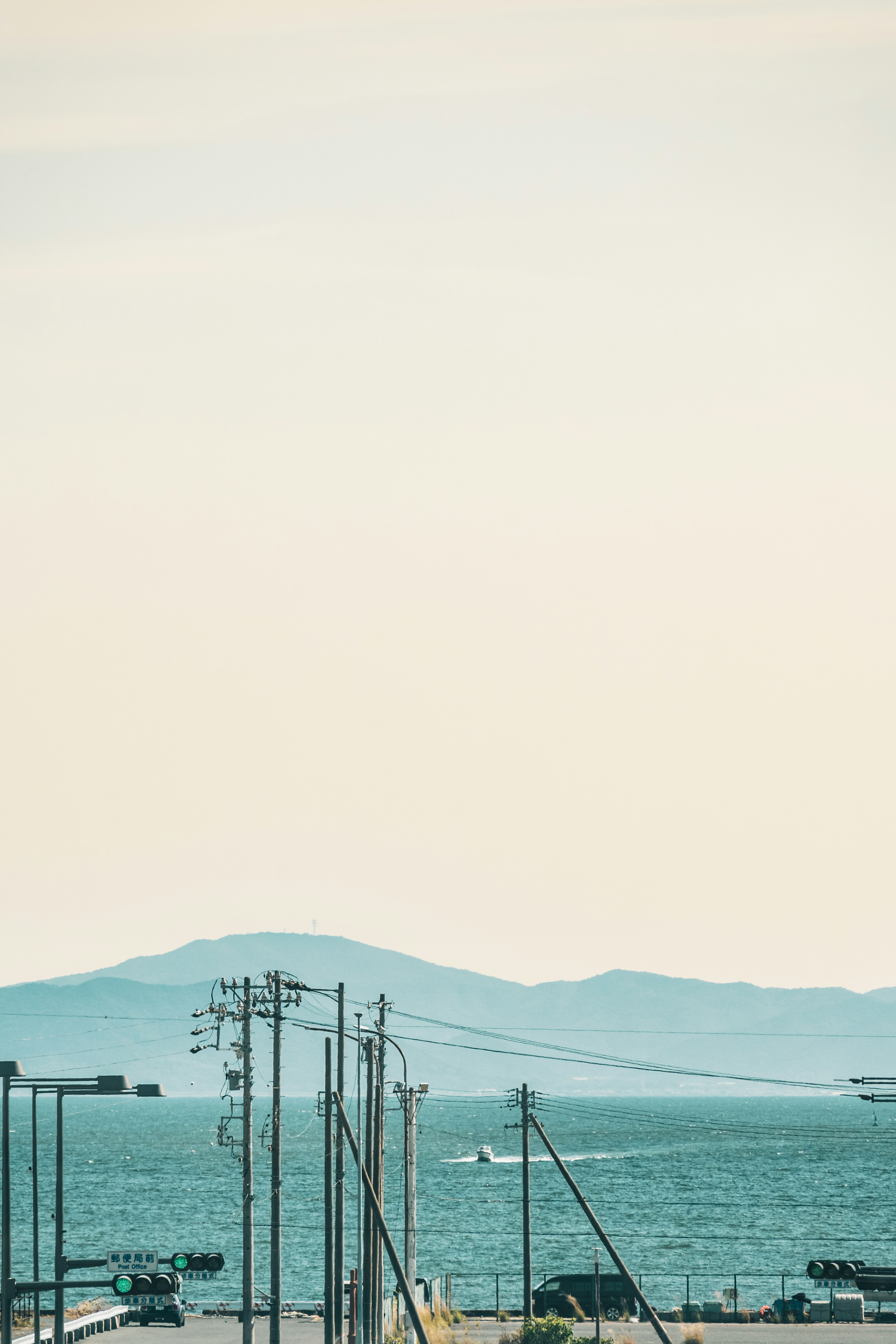 Una vista del mare e delle montagne con linee elettriche in primo piano