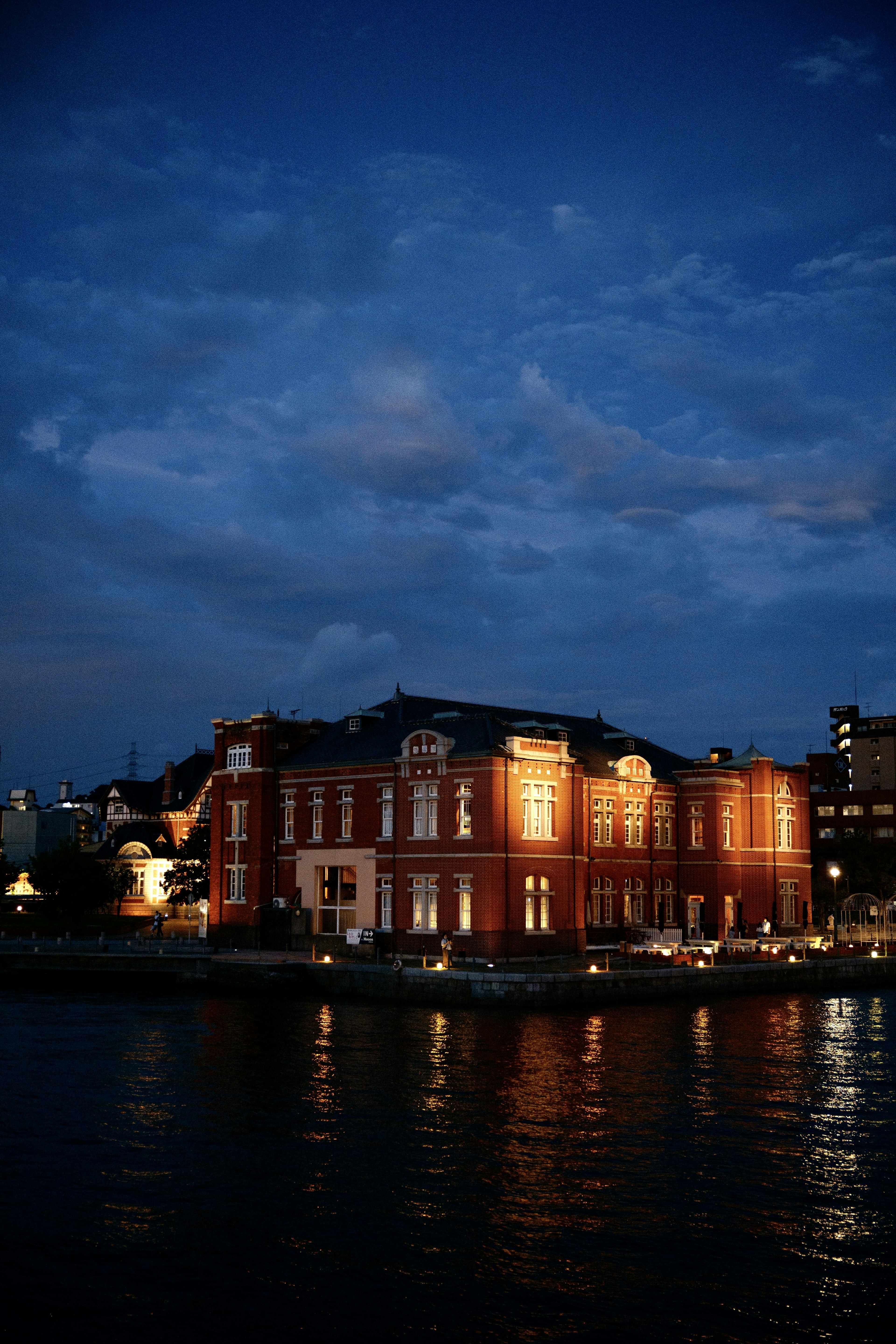 Rotes Backsteingebäude bei Dämmerung am Wasser beleuchtet