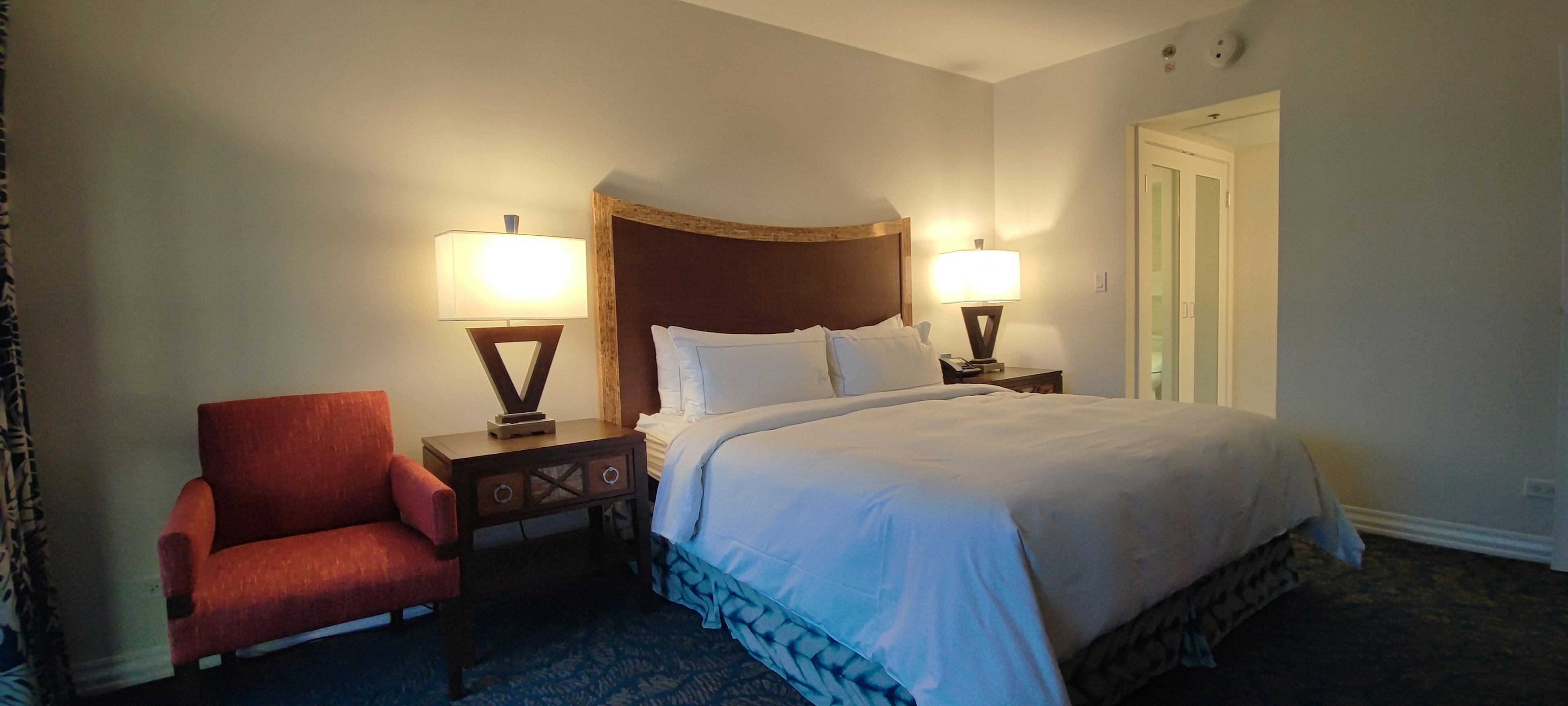 Chambre lumineuse avec un lit double et une chaise rouge