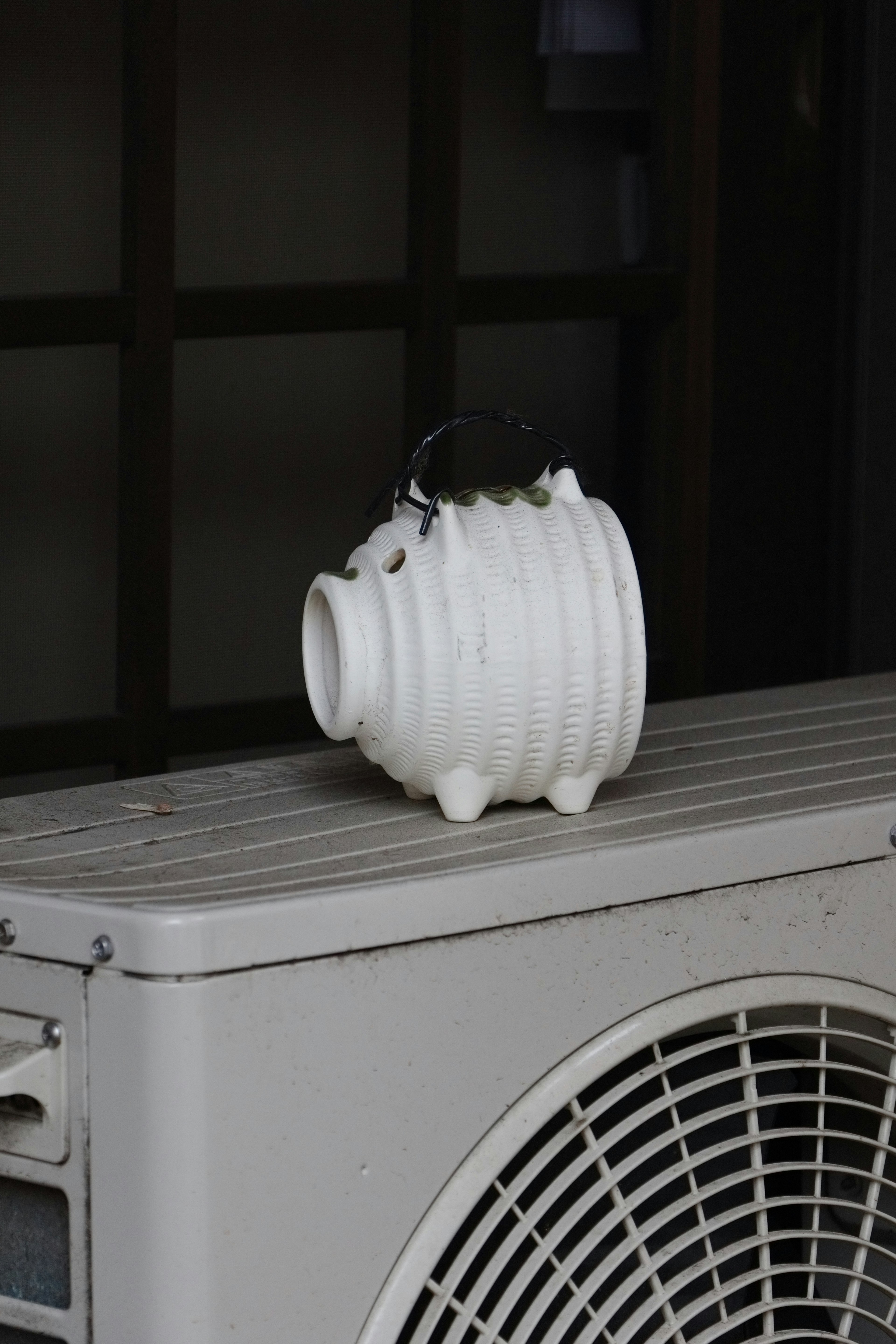 A white ceramic piggy bank sits on top of an air conditioning unit