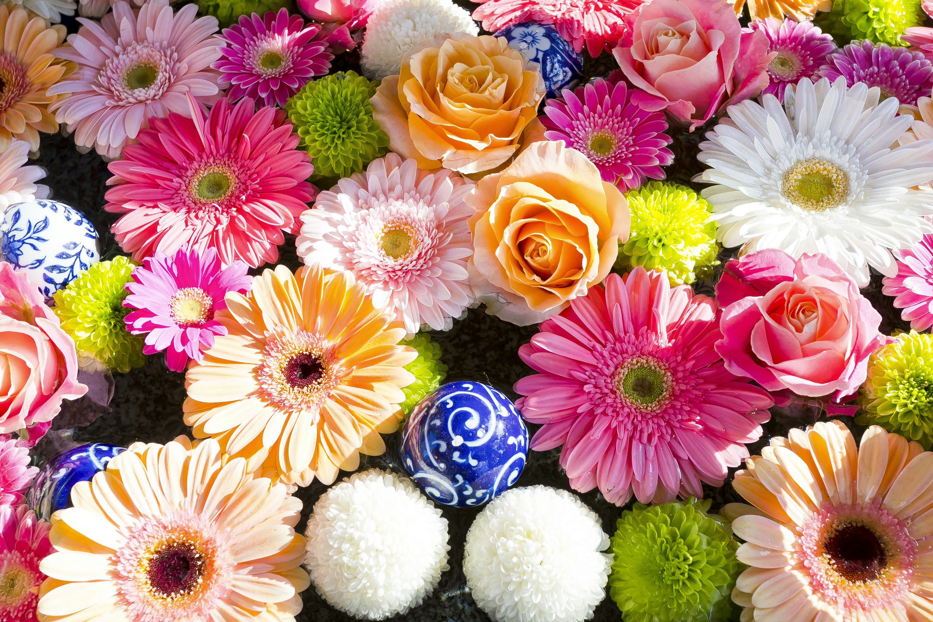 Arreglo colorido de flores con bolas decorativas que incluyen rosas y gerberas