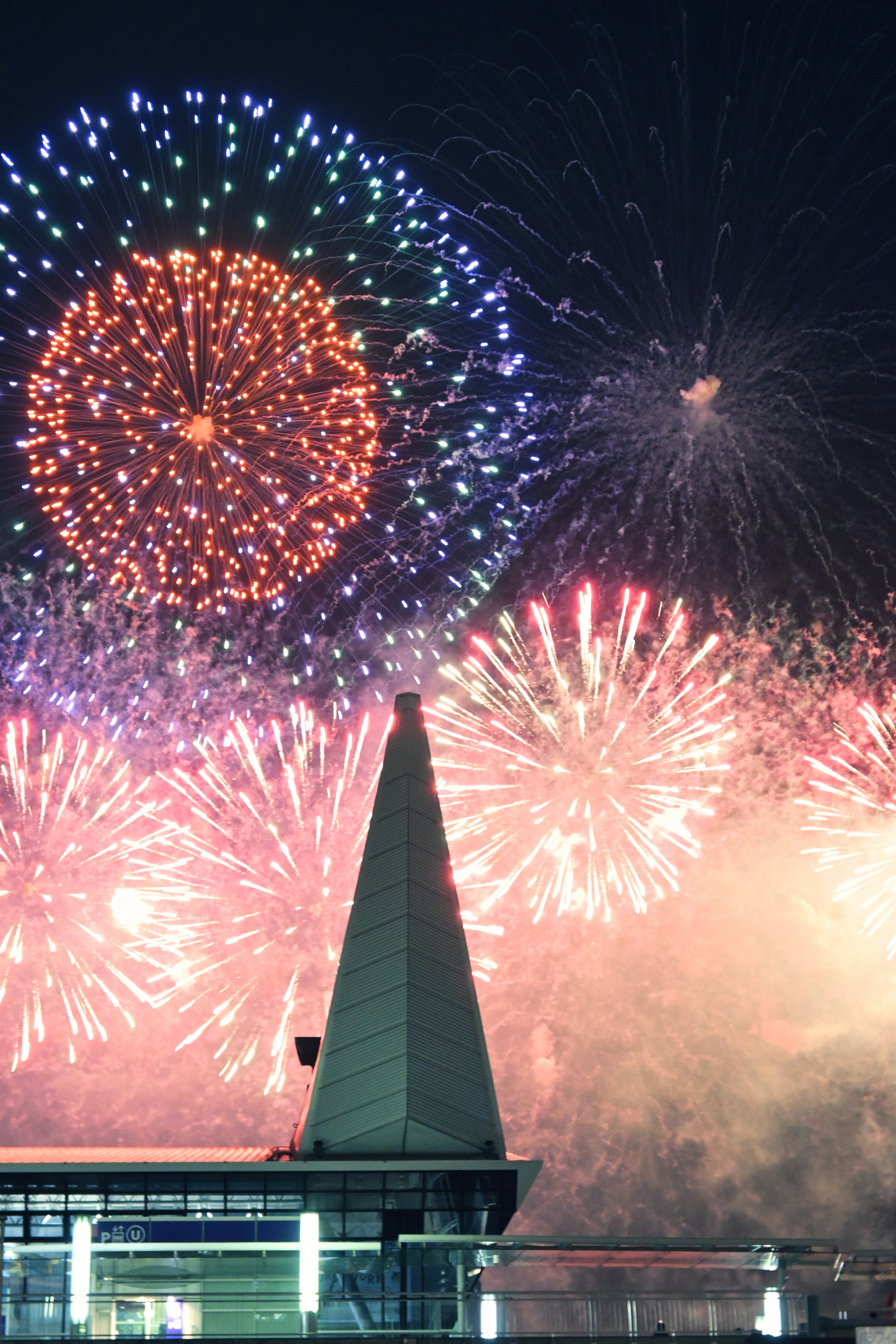 Fuochi d'artificio colorati che illuminano il cielo notturno con un edificio appuntito in primo piano