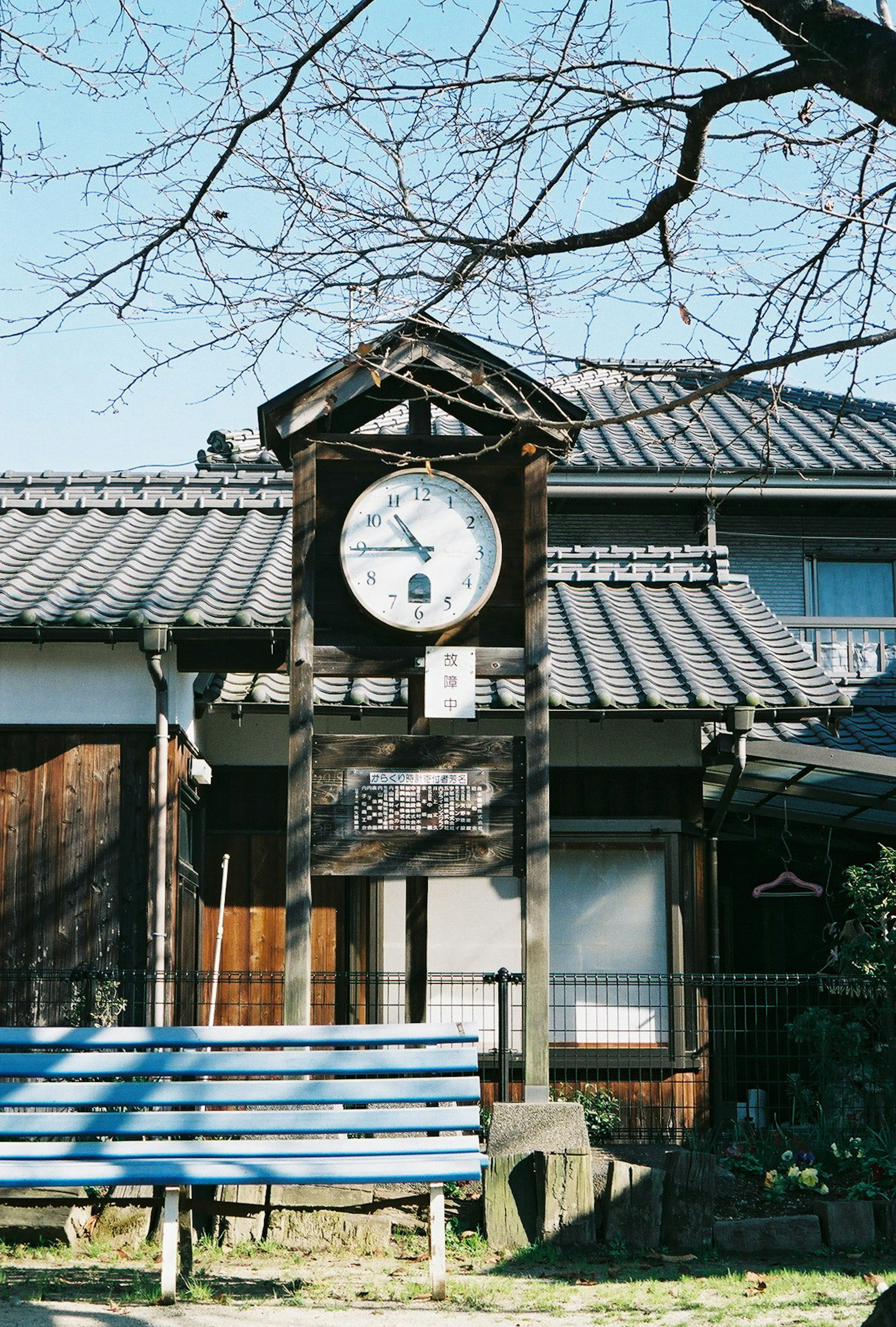 Vecchia torre dell'orologio in legno con una panchina blu in primo piano