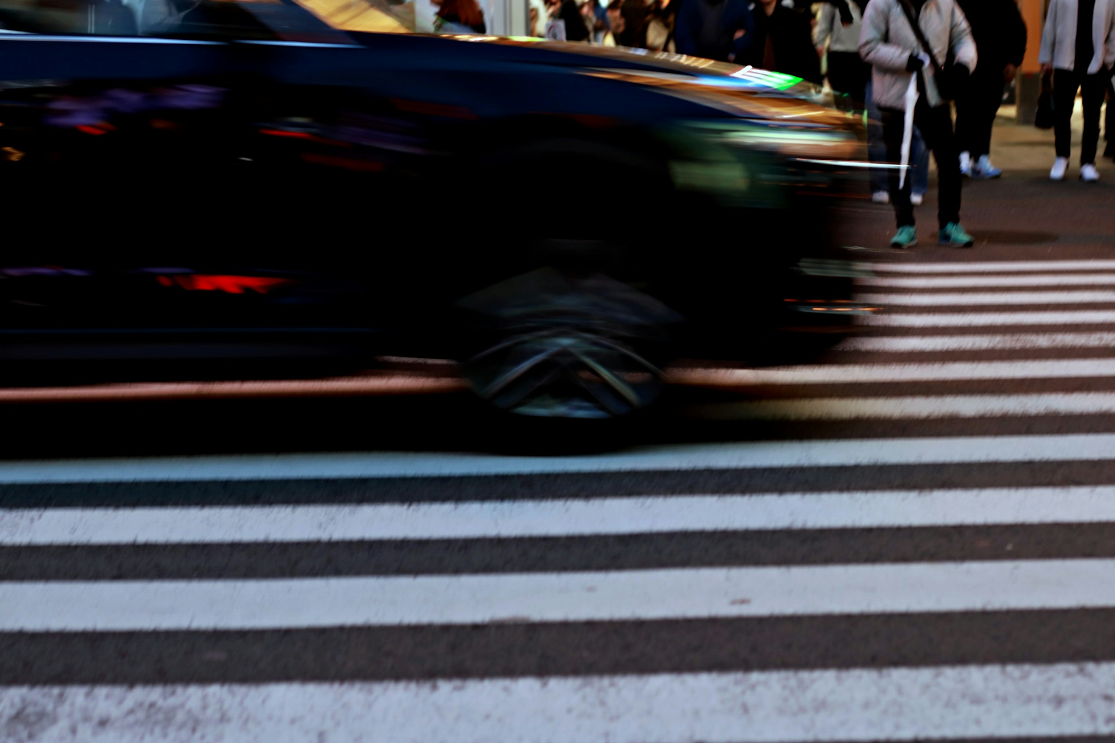 A moving car passing over a crosswalk in an urban setting