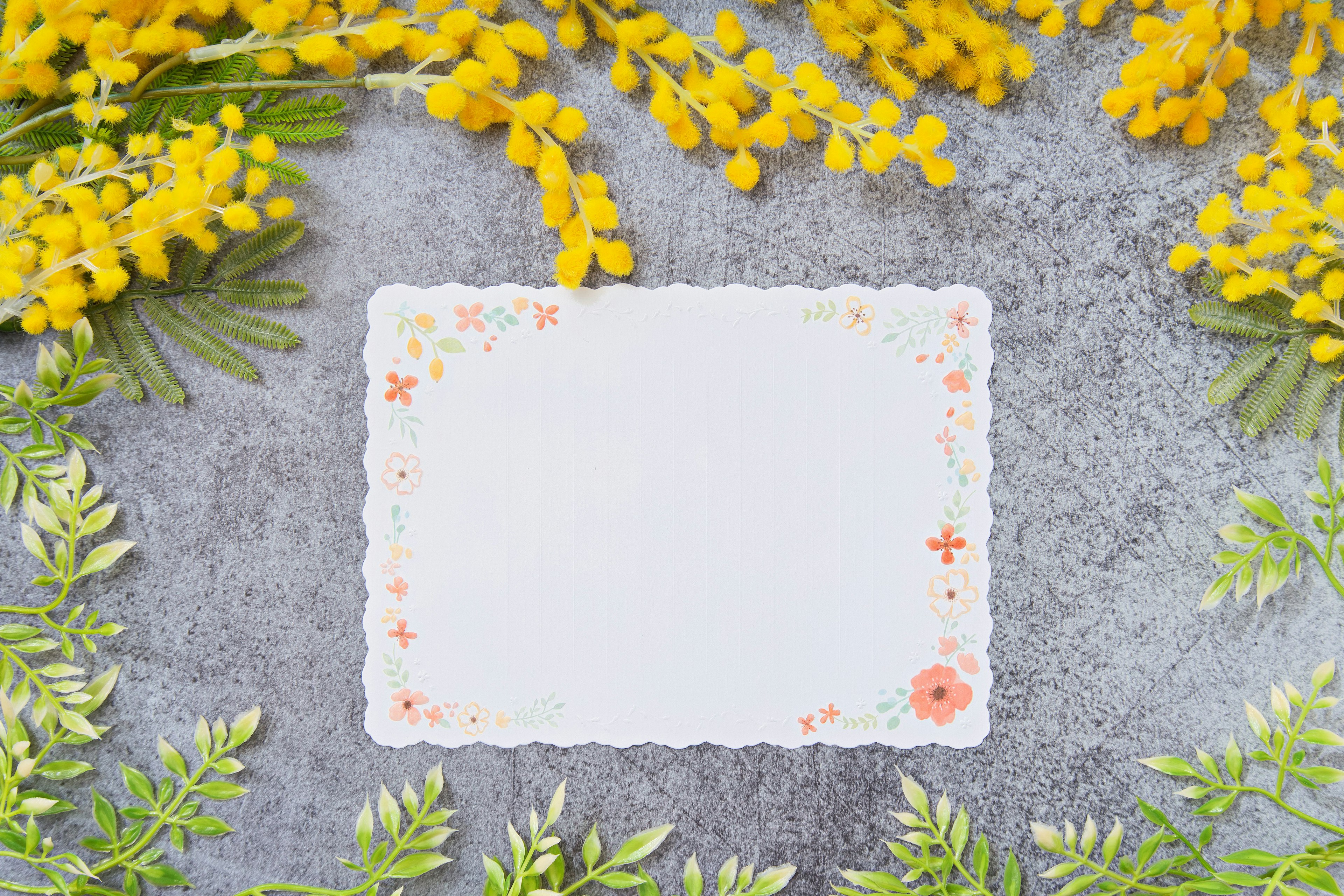 Blank card surrounded by yellow flowers and green leaves