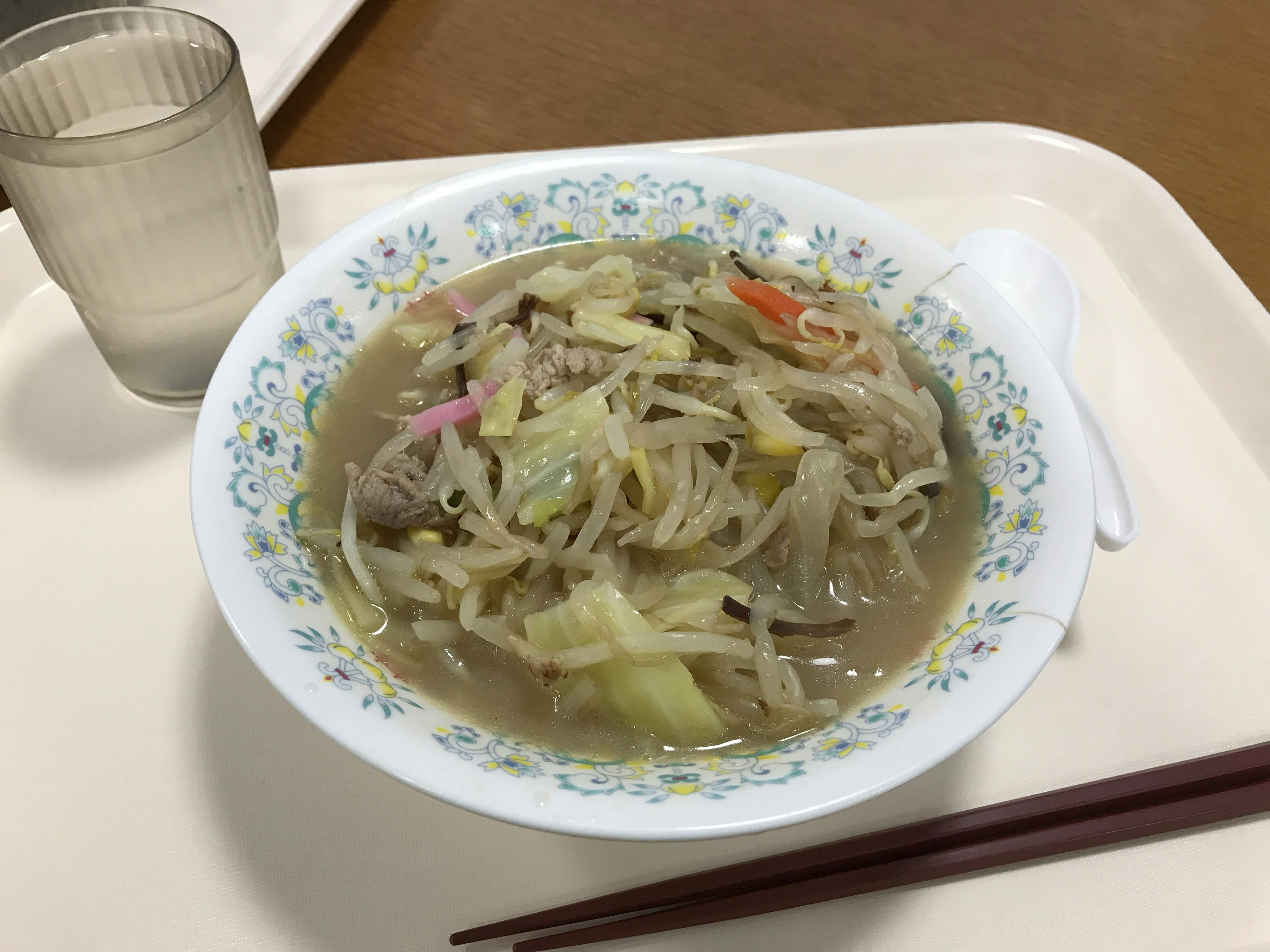 Schüssel mit warmer Gemüse- und Fleischsuppe transparentes Wasserglas Einweg-Löffel und Essstäbchen