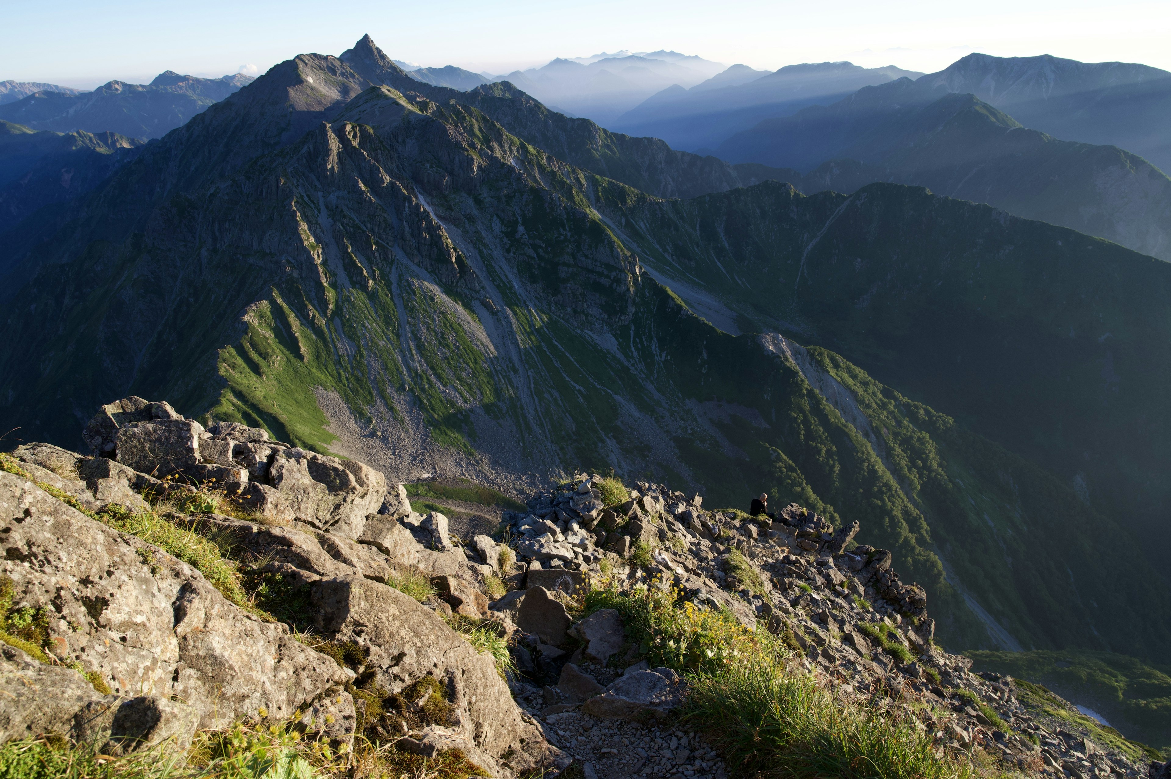 Vista panoramica dalla cima di montagne verdi con terreno roccioso