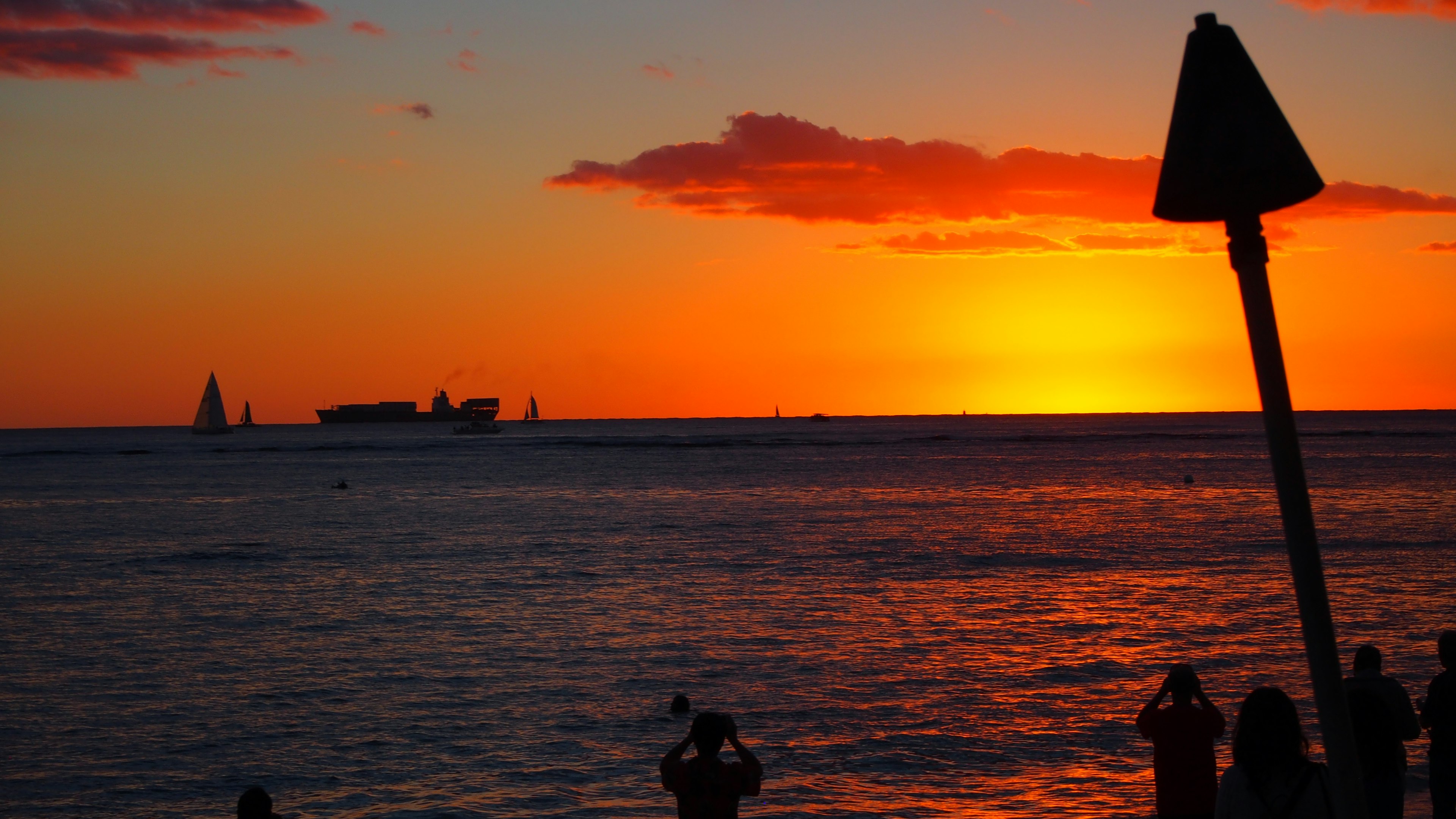 A beautiful sunset over the ocean with silhouettes of people