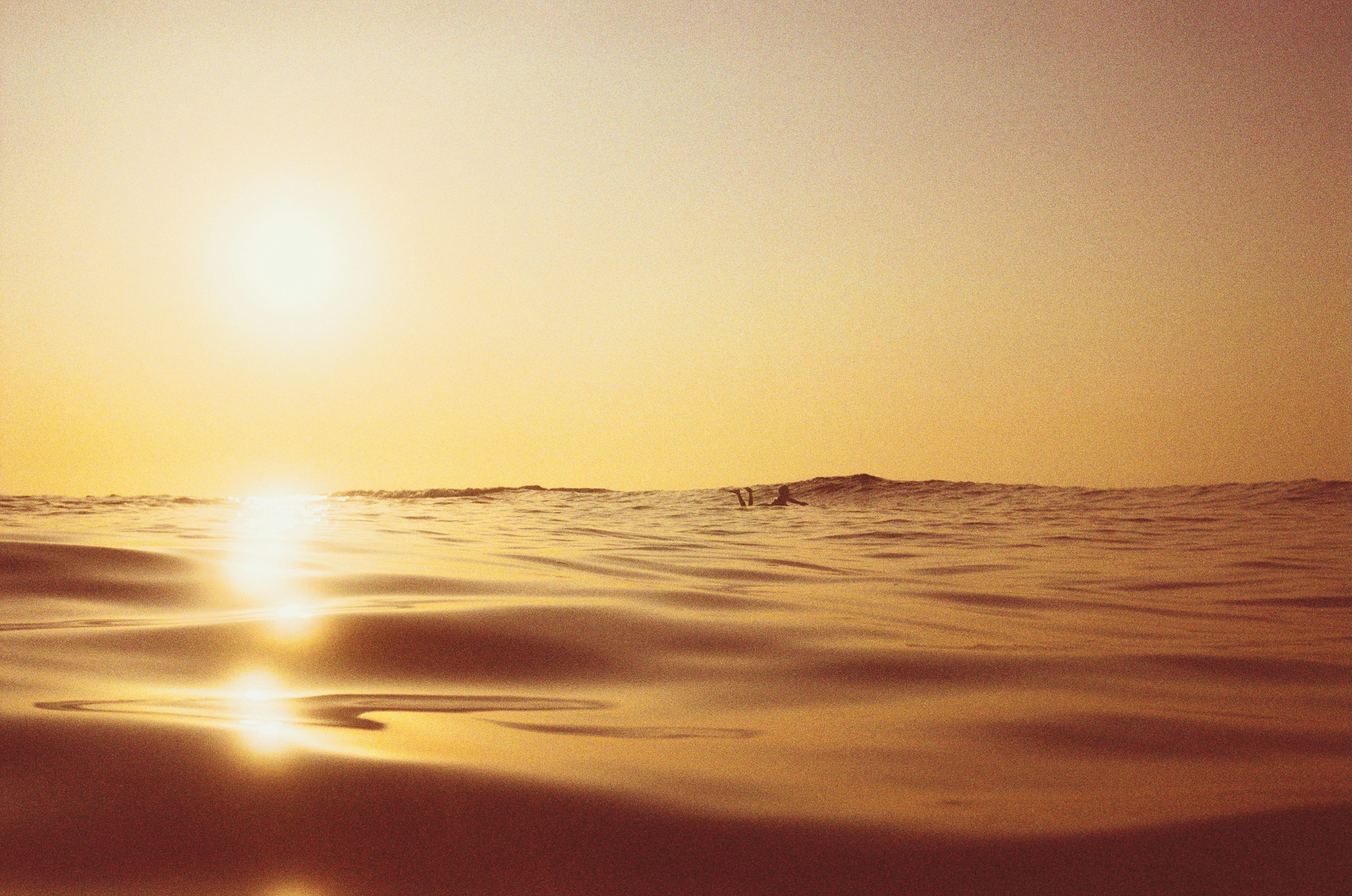 Superficie dell'oceano calmo che riflette il bagliore del tramonto