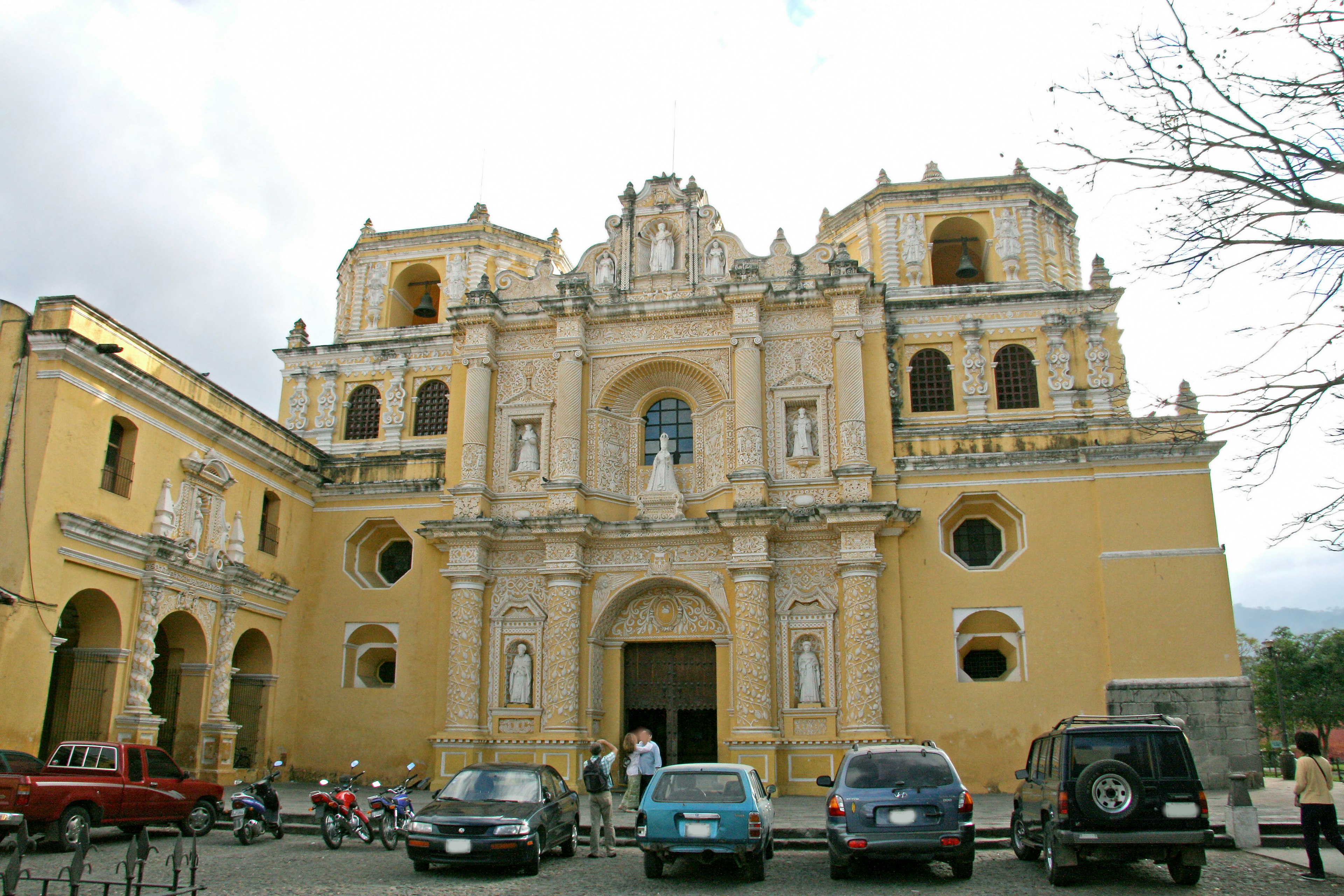 Beautiful yellow church facade with surrounding cars