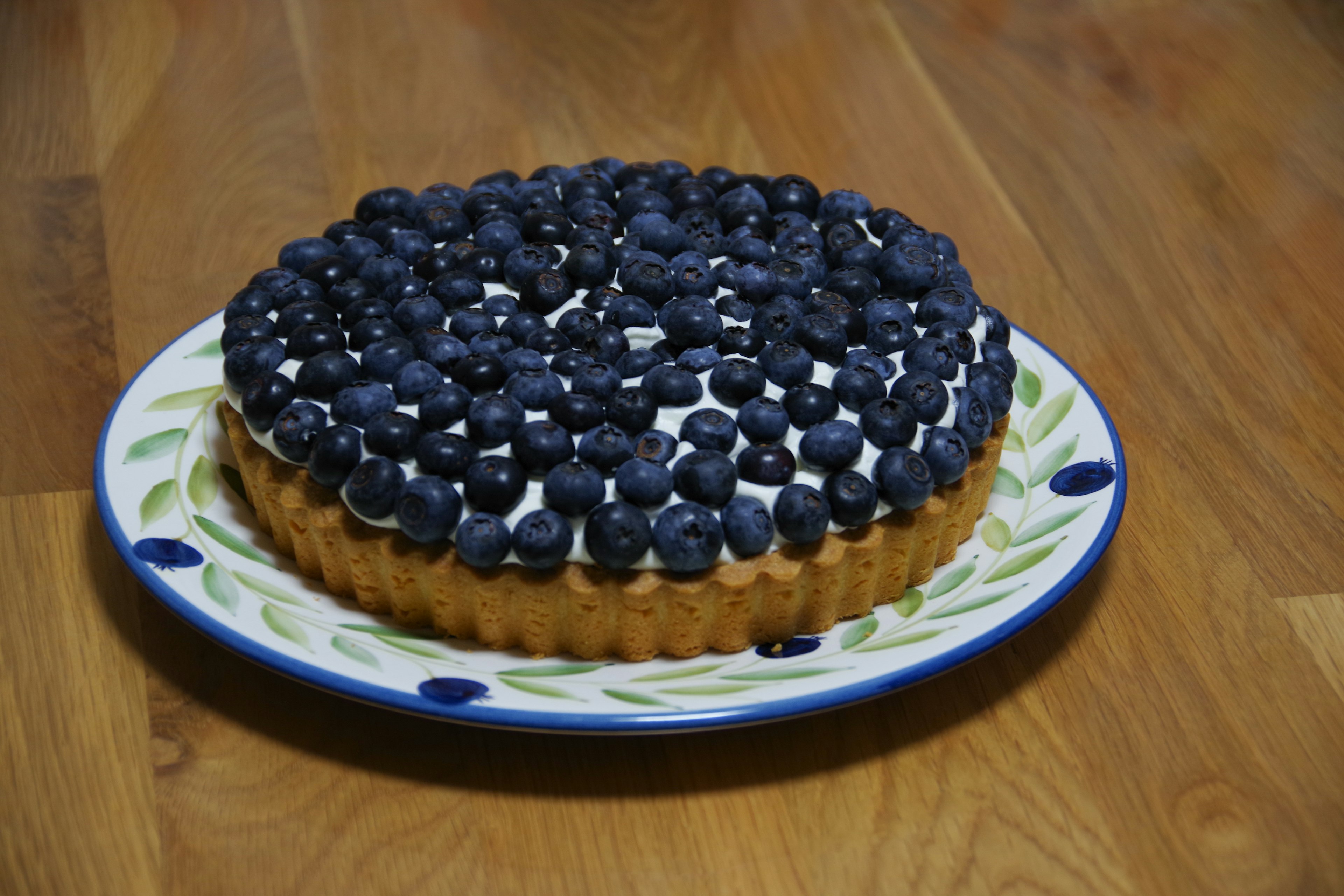 Blueberry tart topped with fresh blueberries on a decorative plate