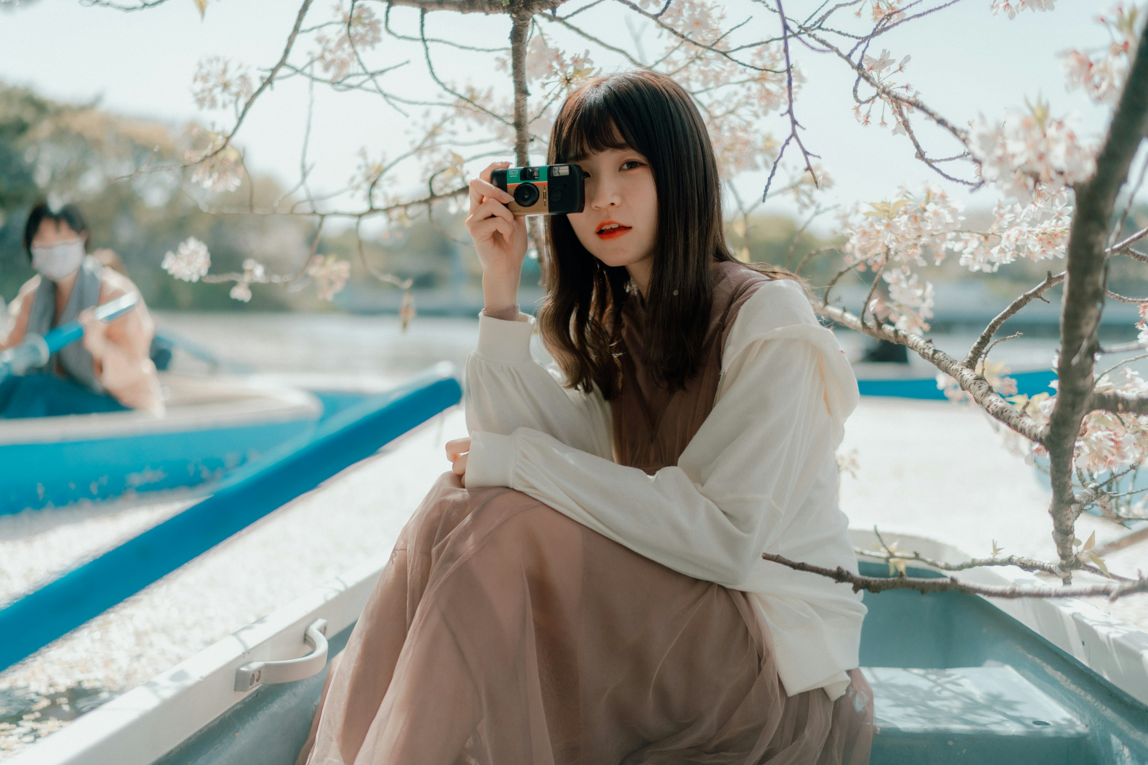 Portrait d'une femme tenant un appareil photo sous un cerisier en fleurs