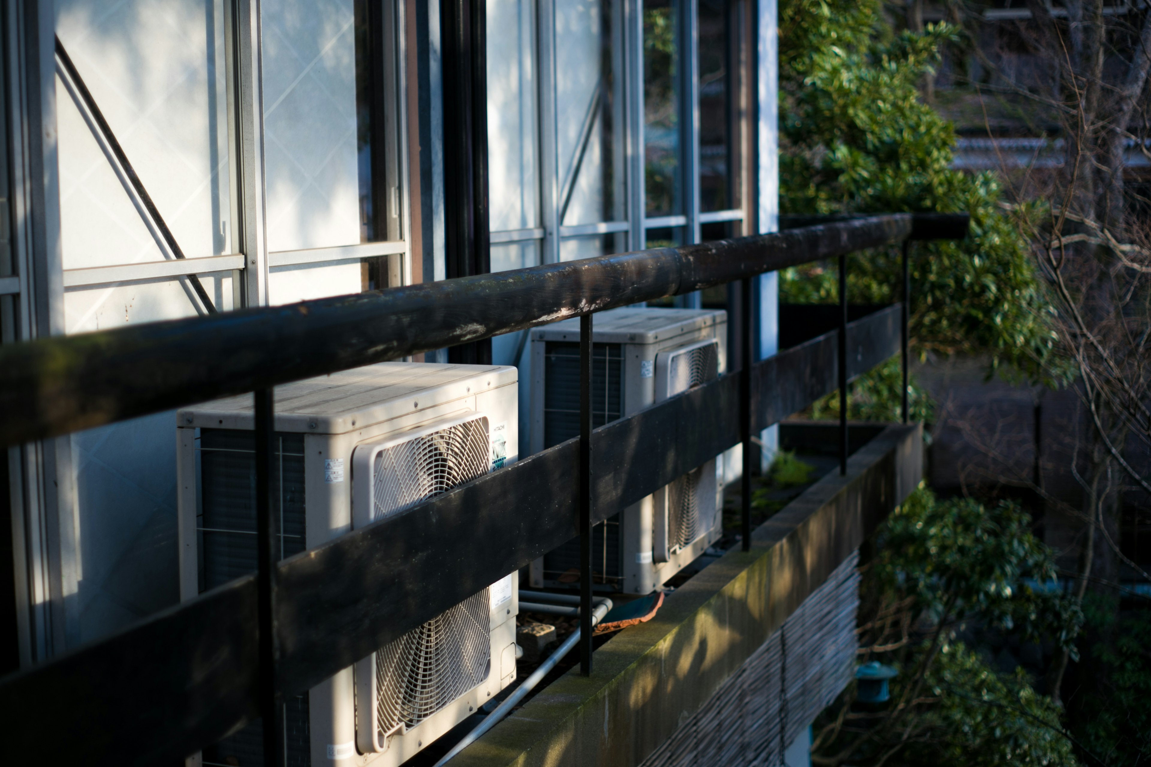 Air conditioning units mounted on a balcony with greenery