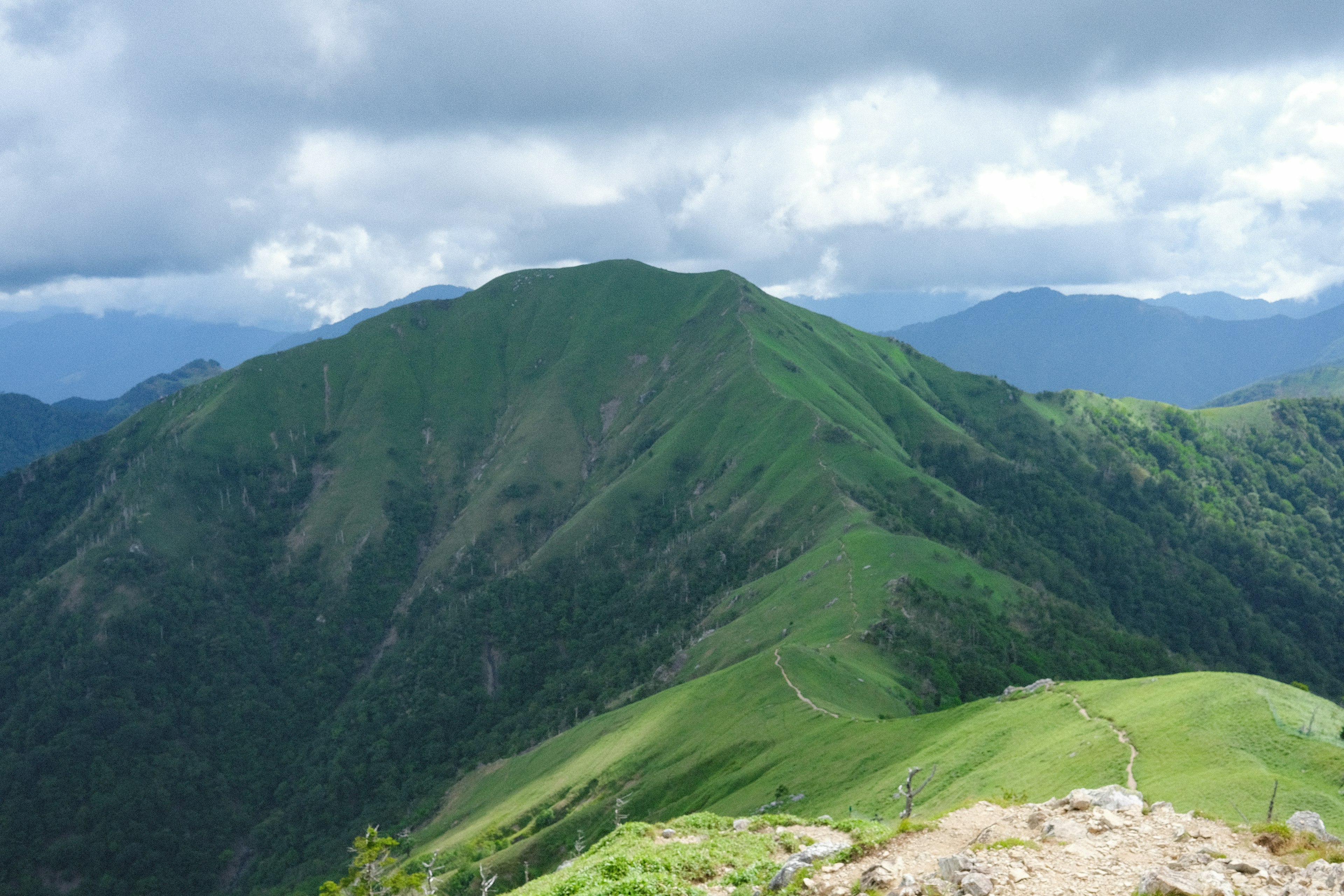 Scenic view of green mountains under a cloudy sky