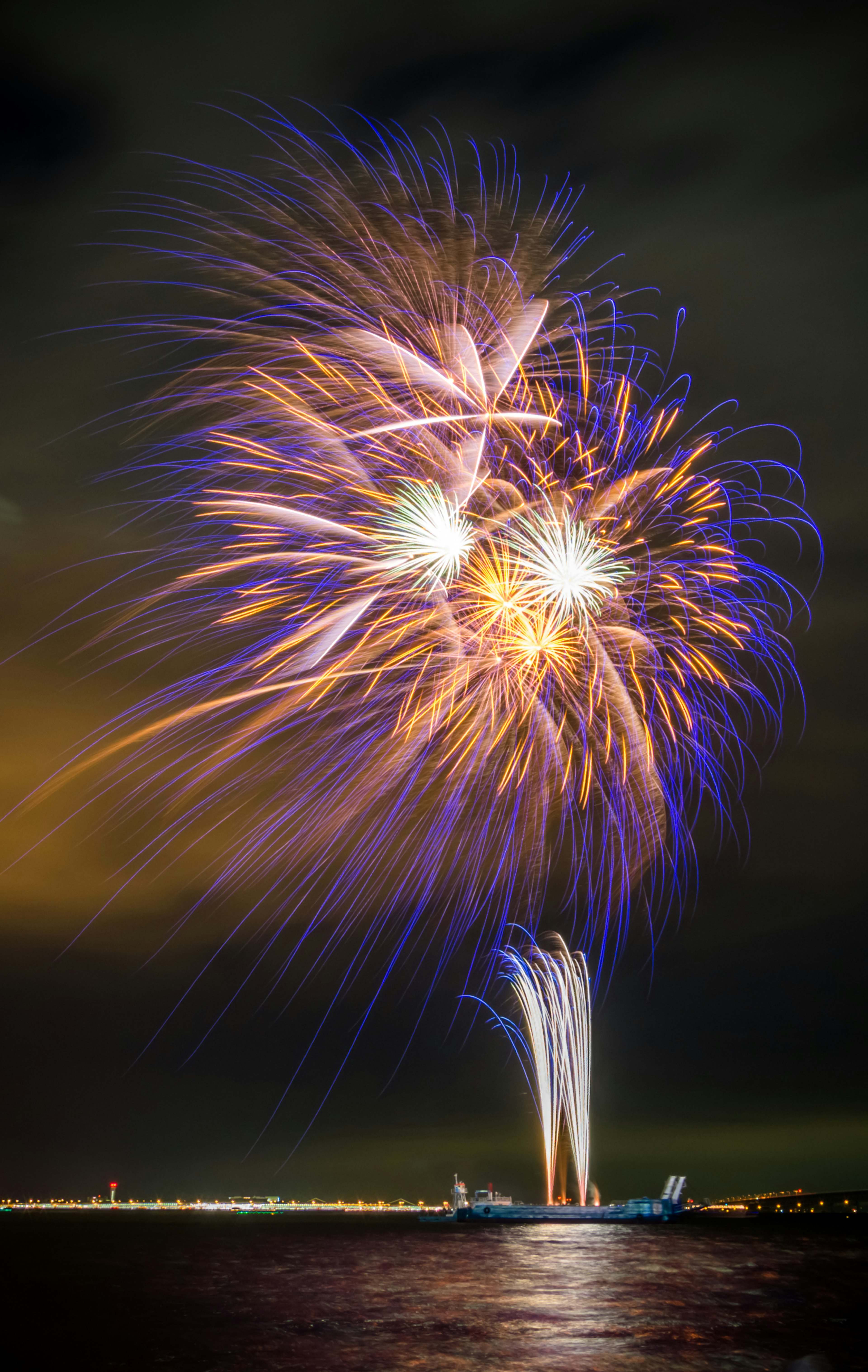 夜空に広がる鮮やかな花火のショーと水面に映る光