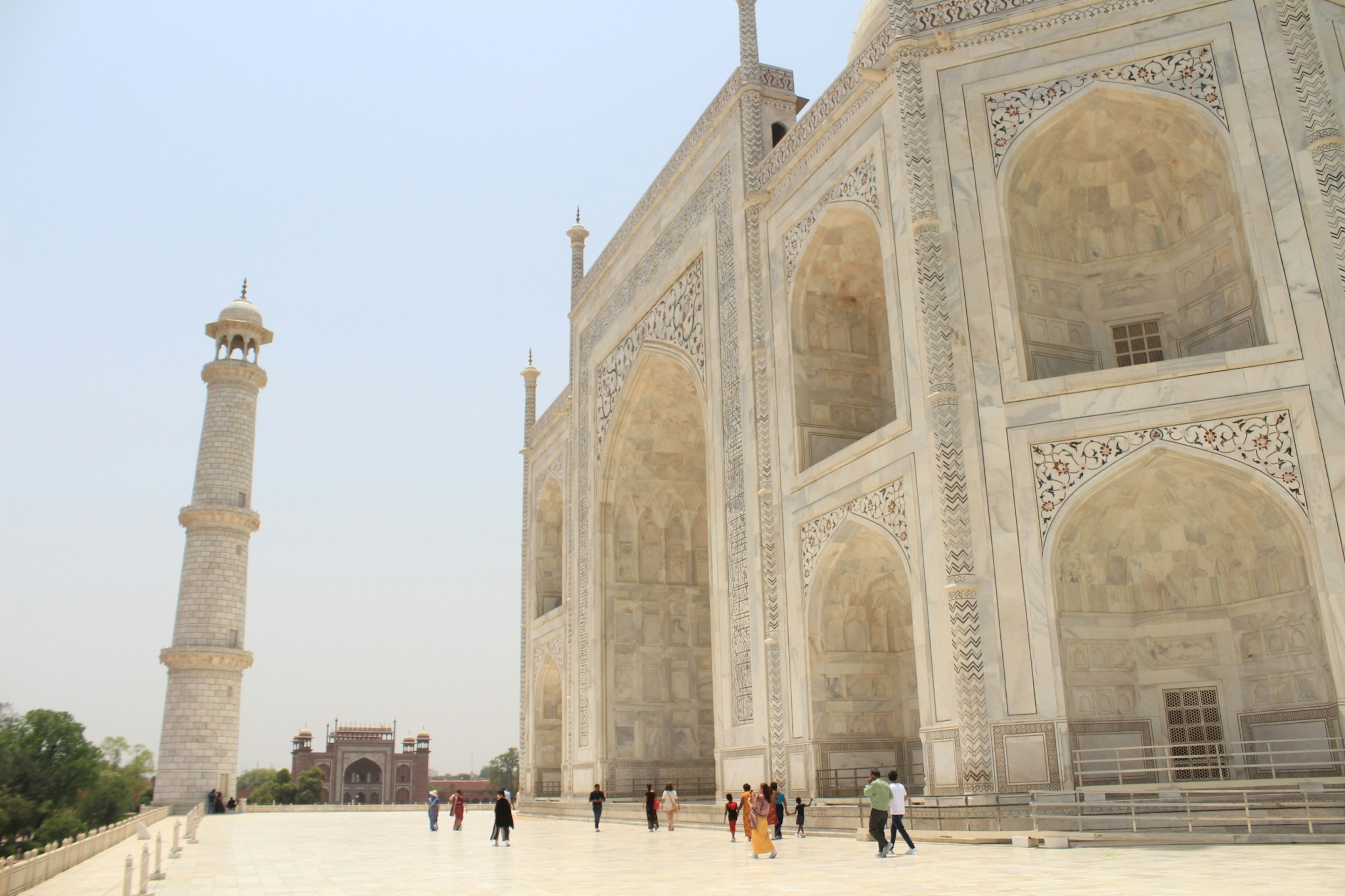 Exterior de mármol blanco del Taj Mahal con visitantes