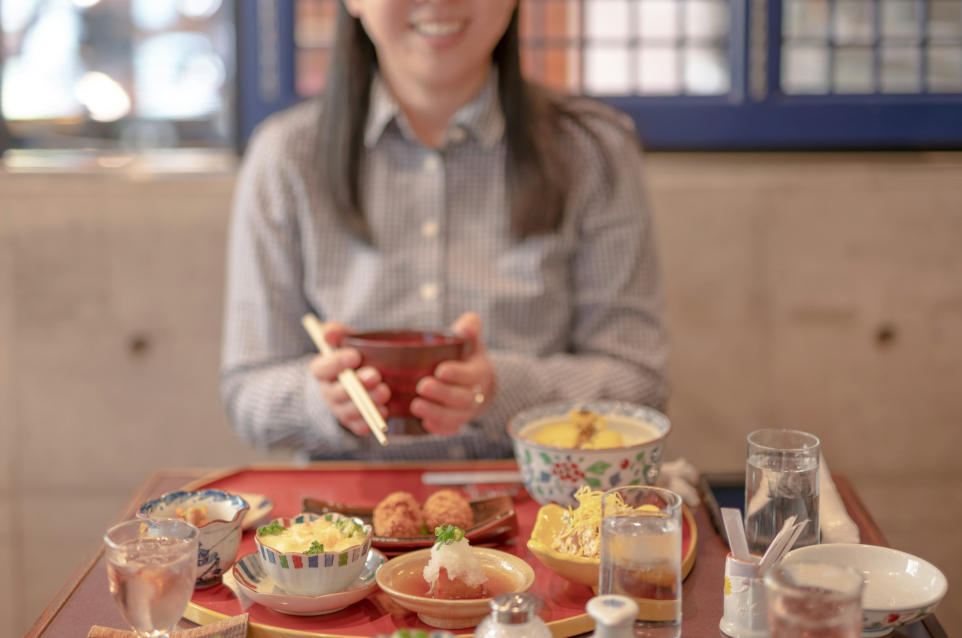 女性がテーブルに並べられた料理を前に笑顔でいる様子