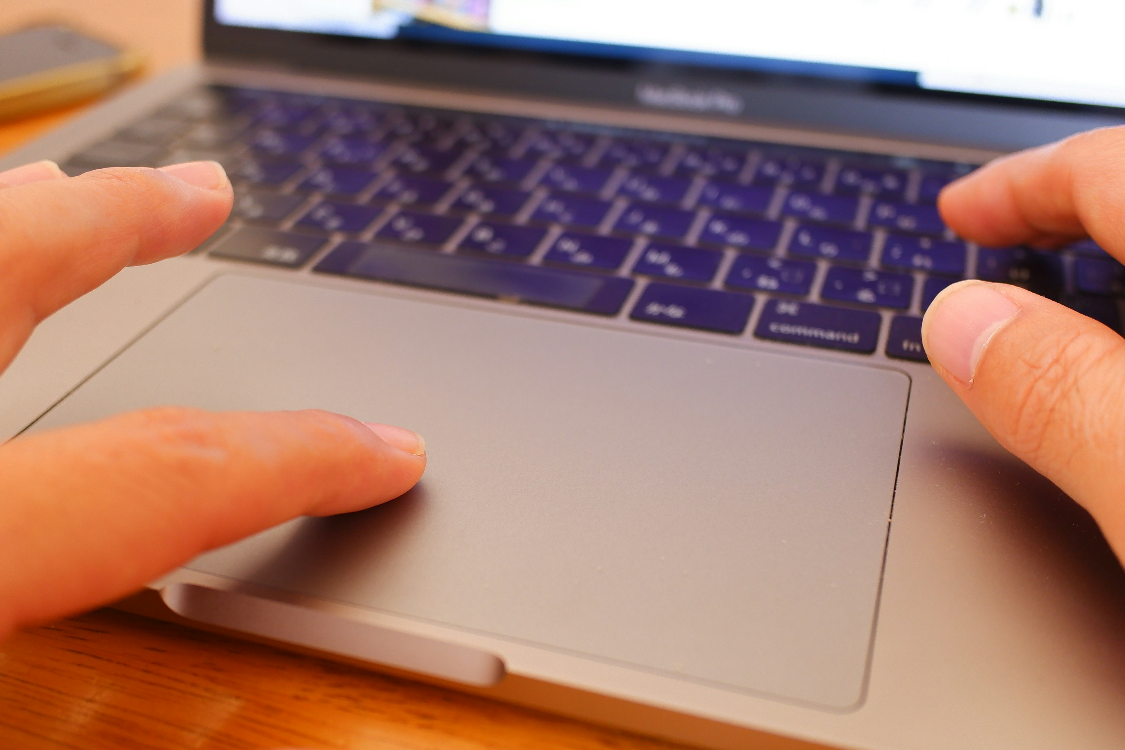 Hands resting on a laptop keyboard and trackpad