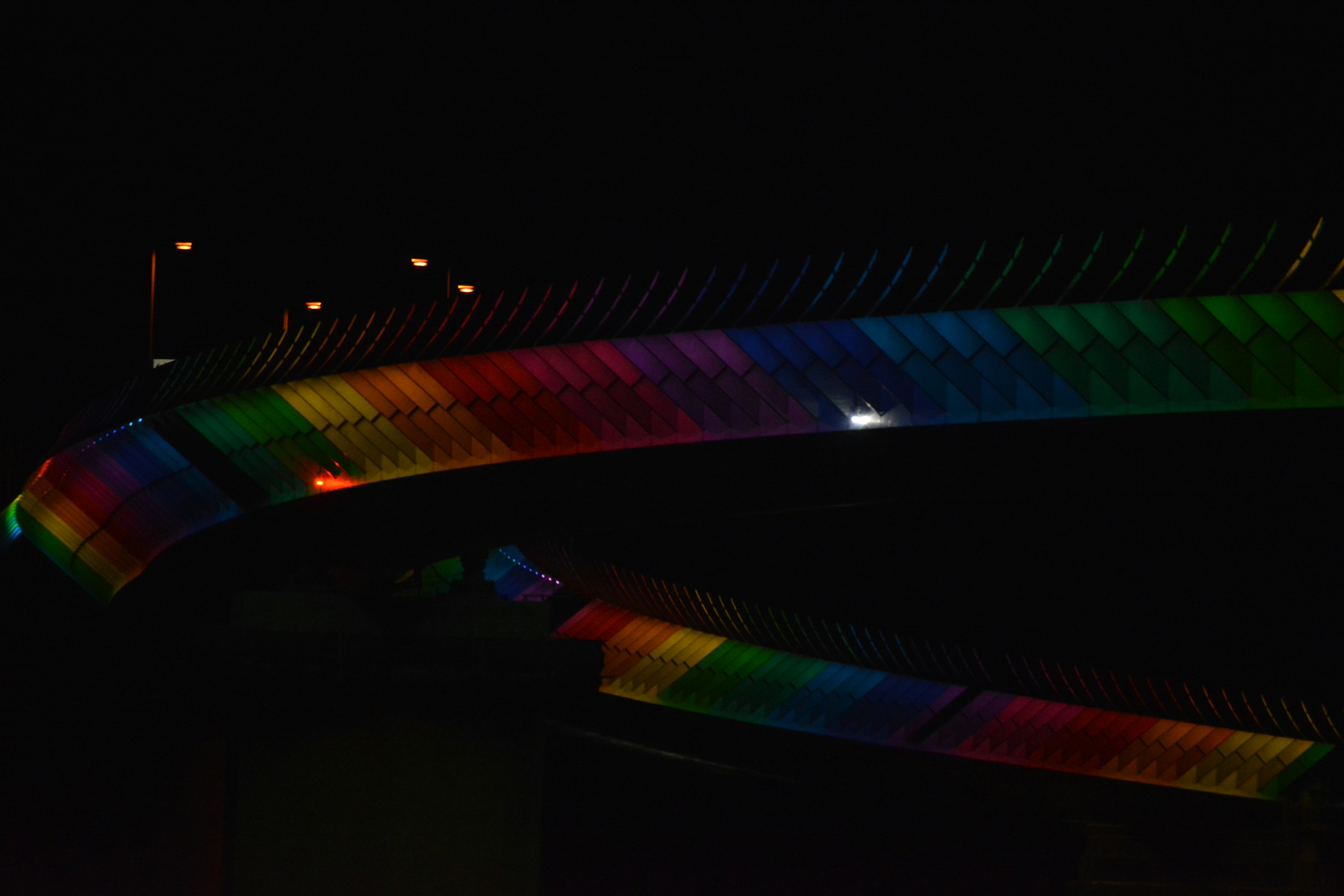 Una sezione di un ponte illuminata con colori arcobaleno vivaci di notte