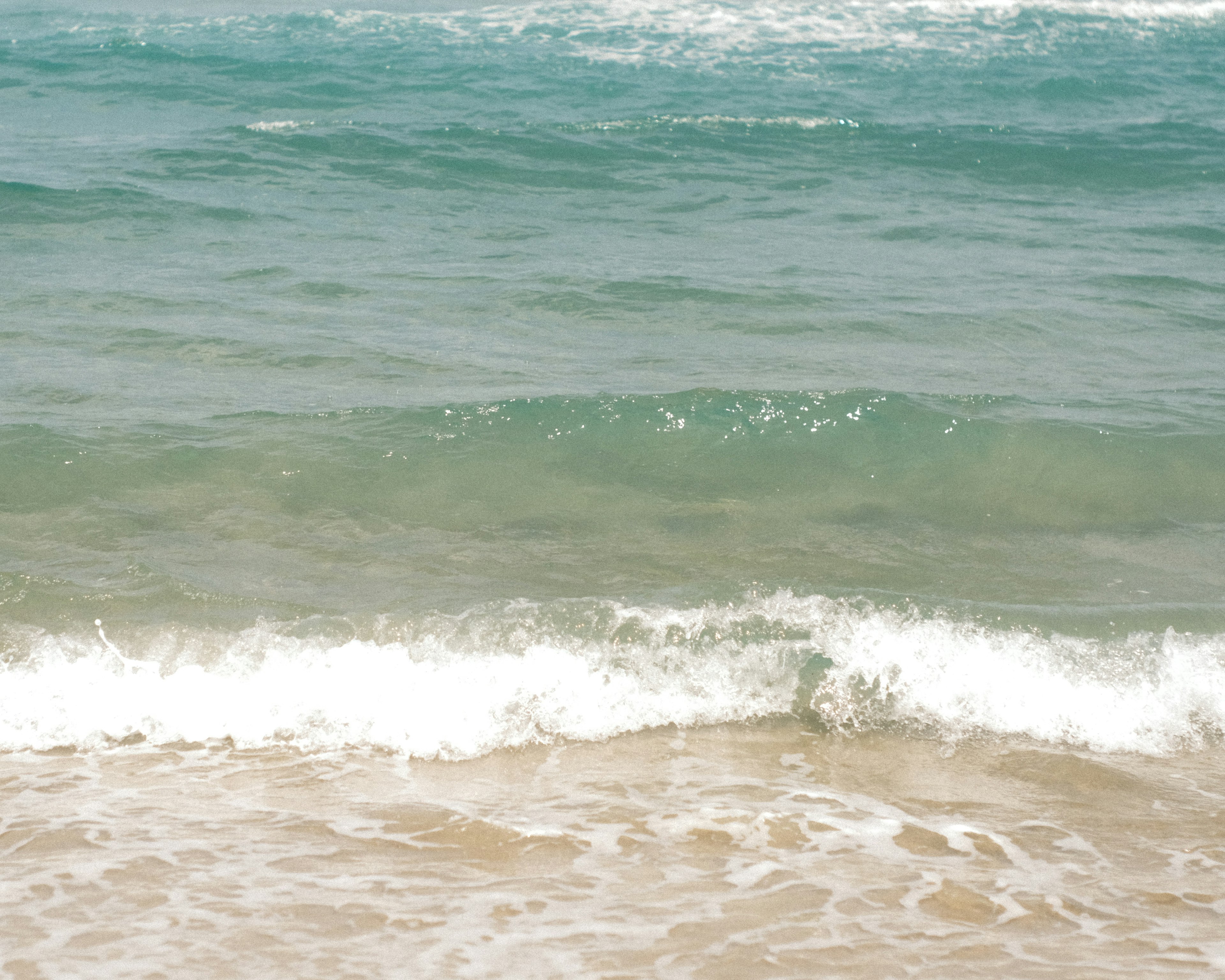 Blue ocean waves gently lapping onto a sandy beach