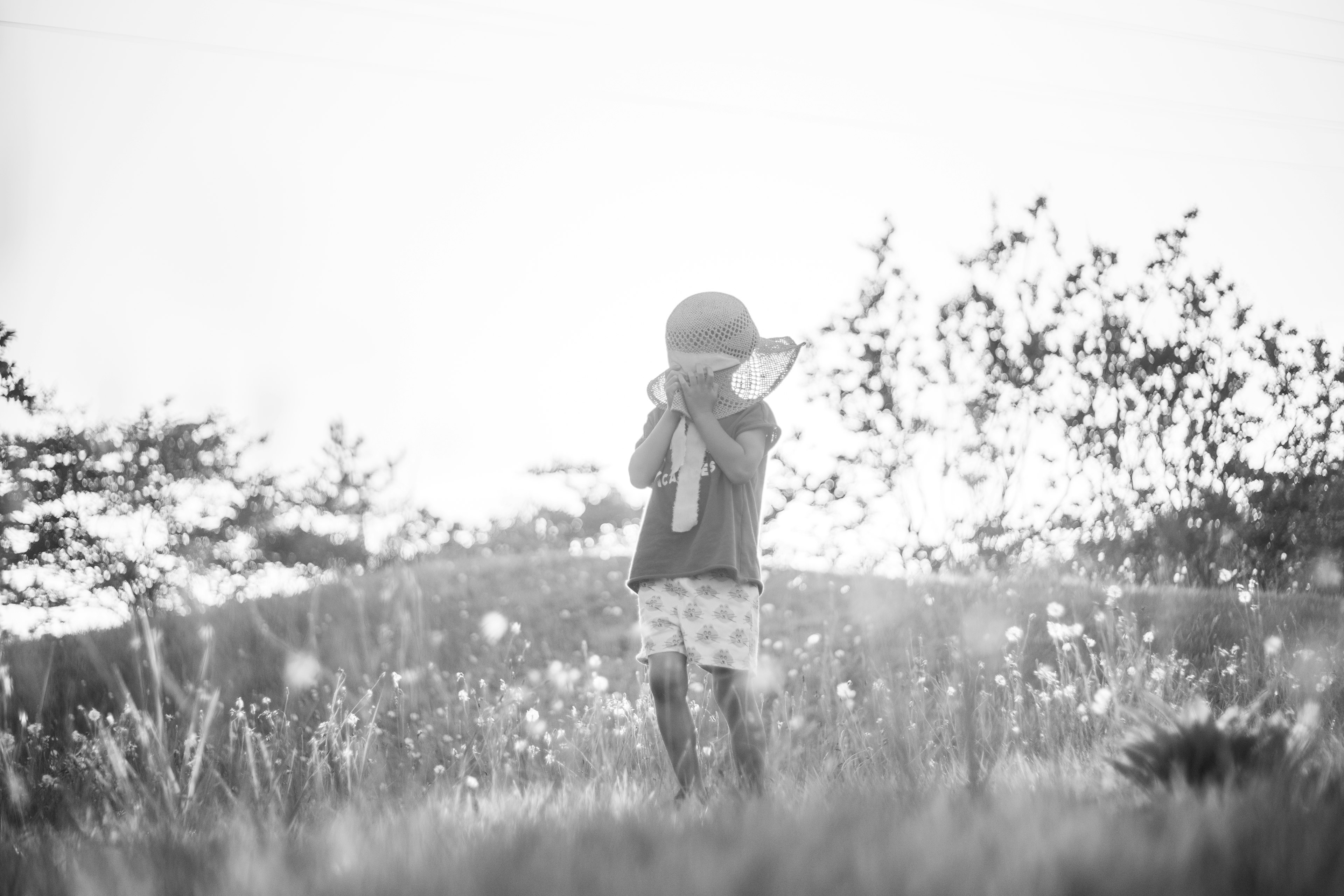 Un niño con un sombrero está de pie en un paisaje en blanco y negro