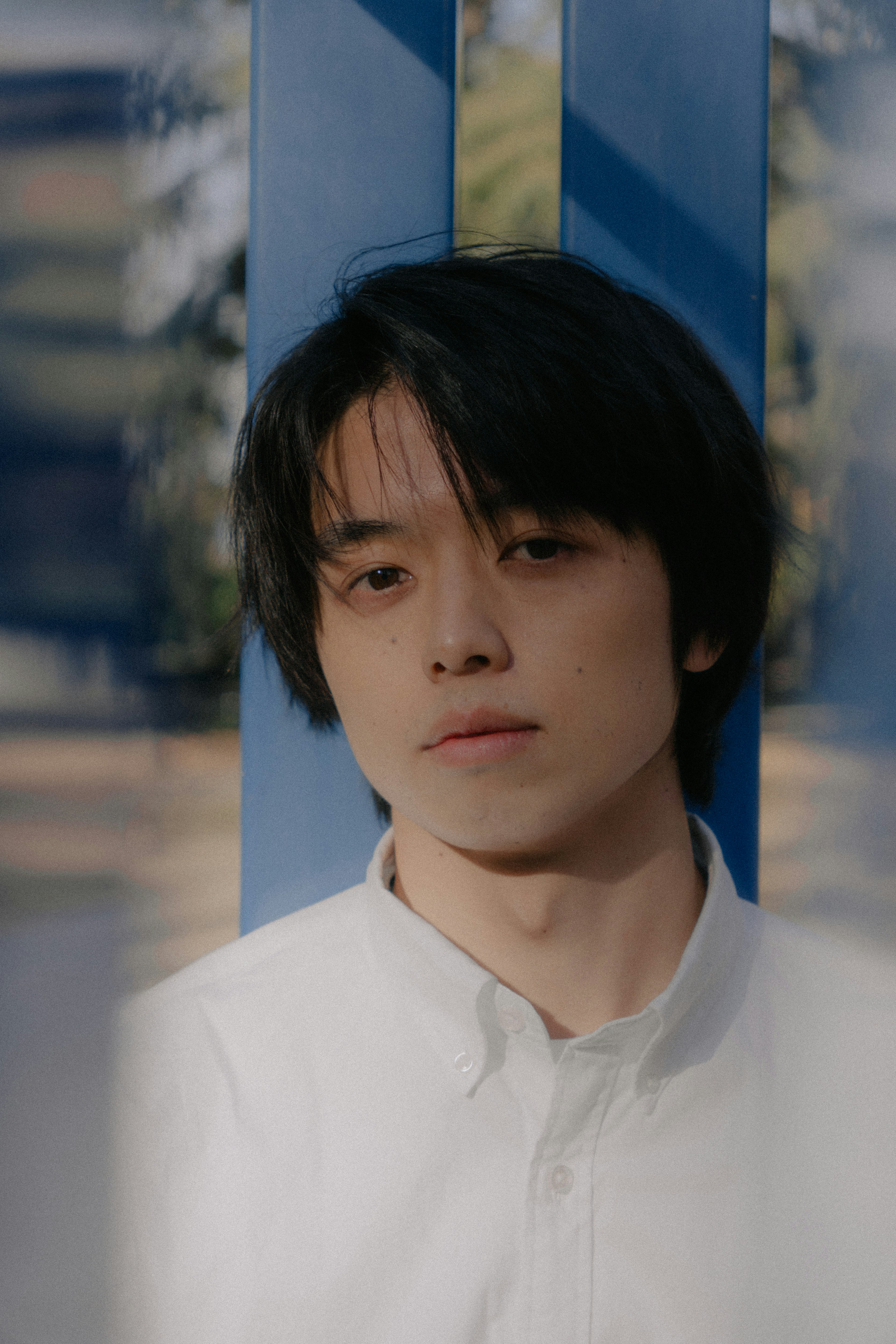 Portrait of a young man standing in front of a blue background