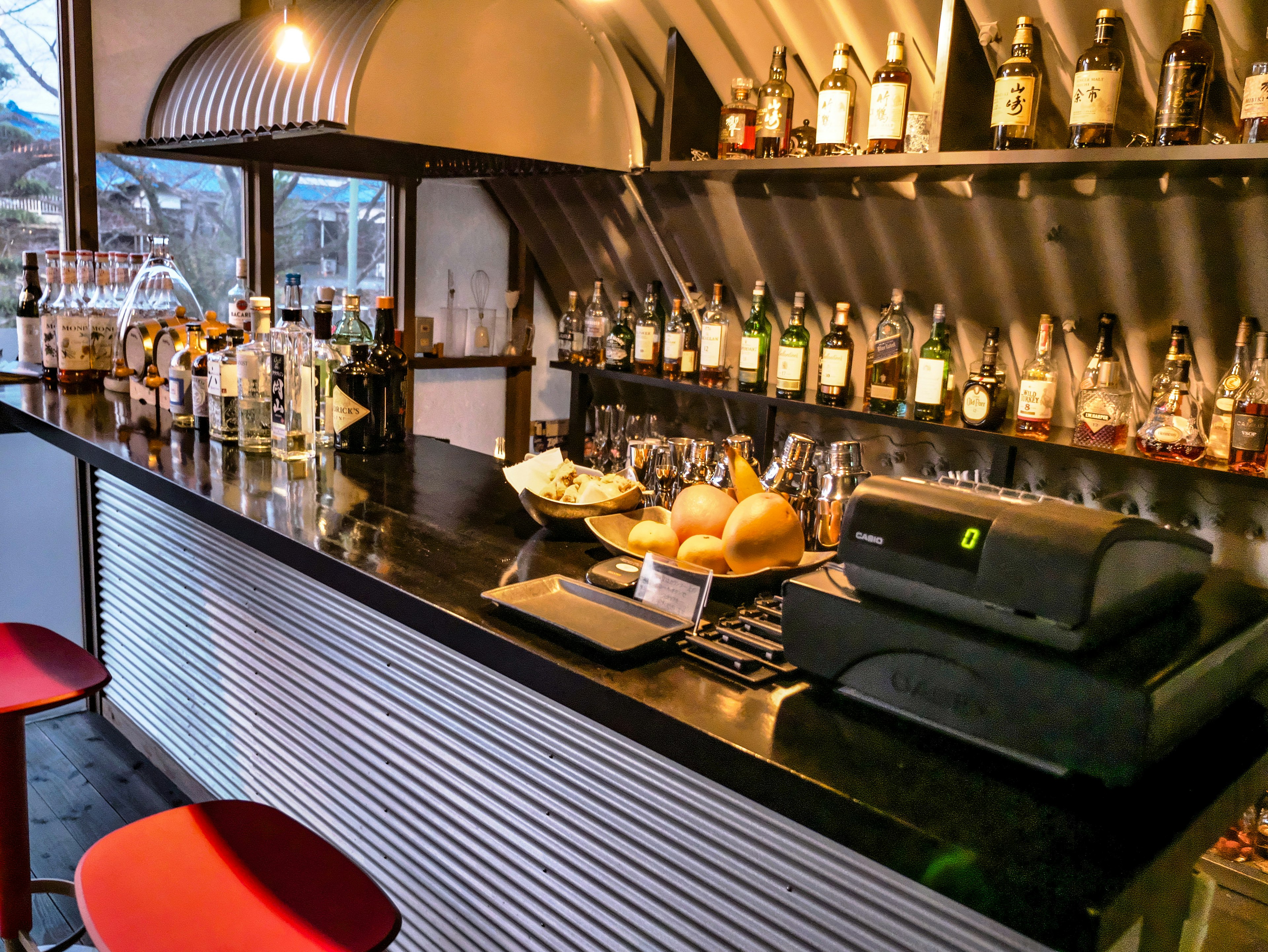 Interior de un bar con una variedad de botellas y bebidas en el mostrador