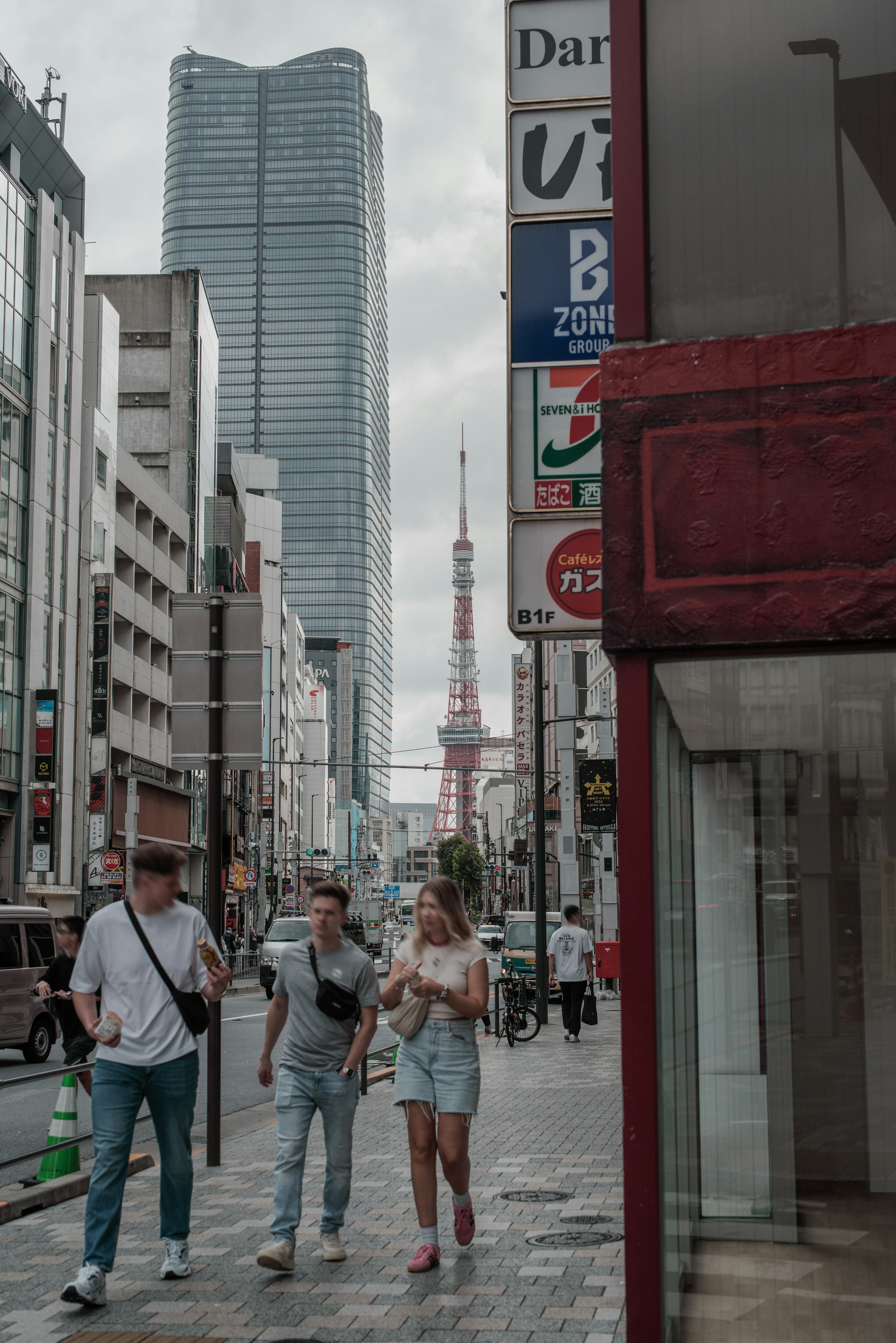 Orang-orang yang berjalan di jalanan Tokyo dengan Menara Tokyo di latar belakang