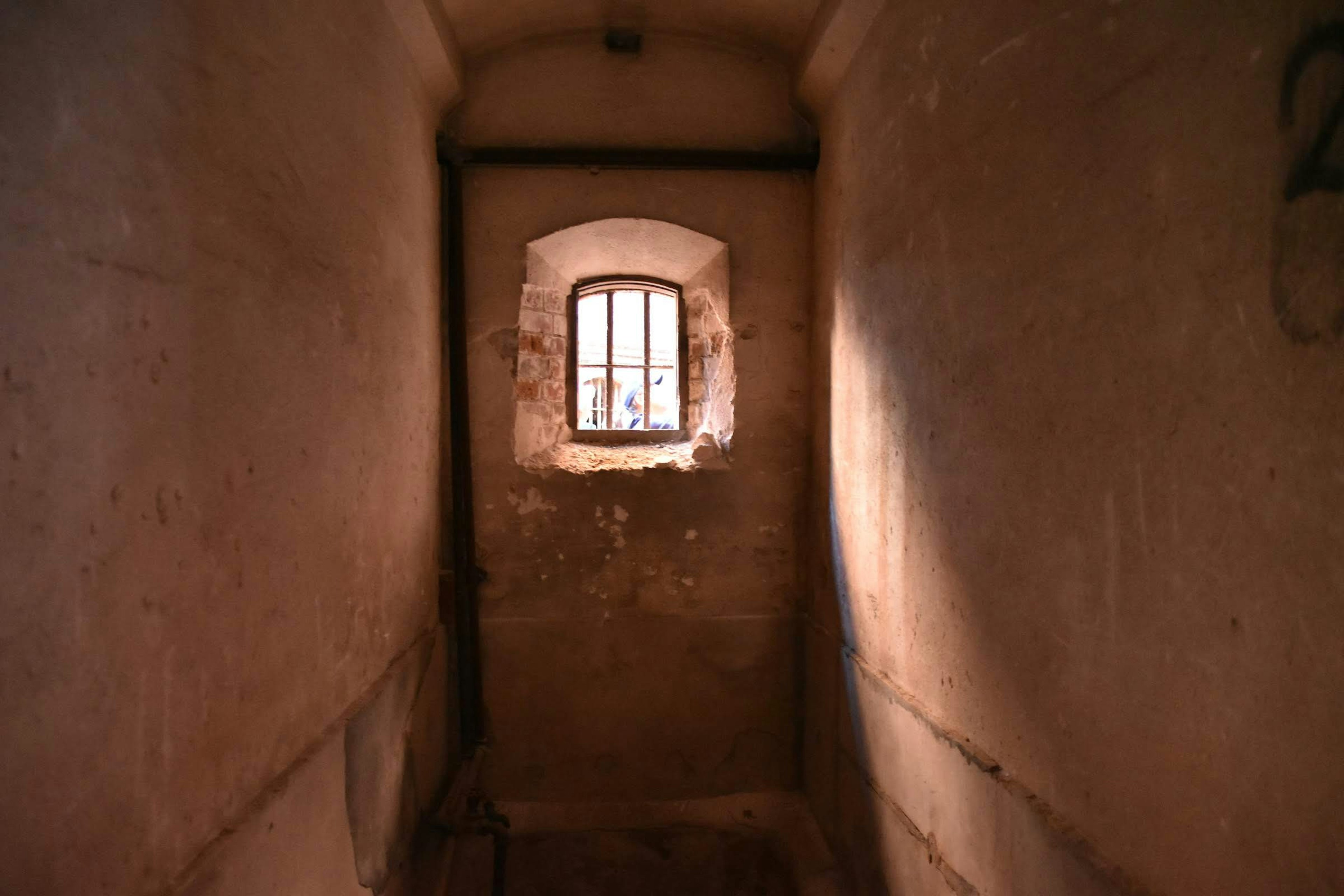 Narrow hallway leading to a small window in an old building