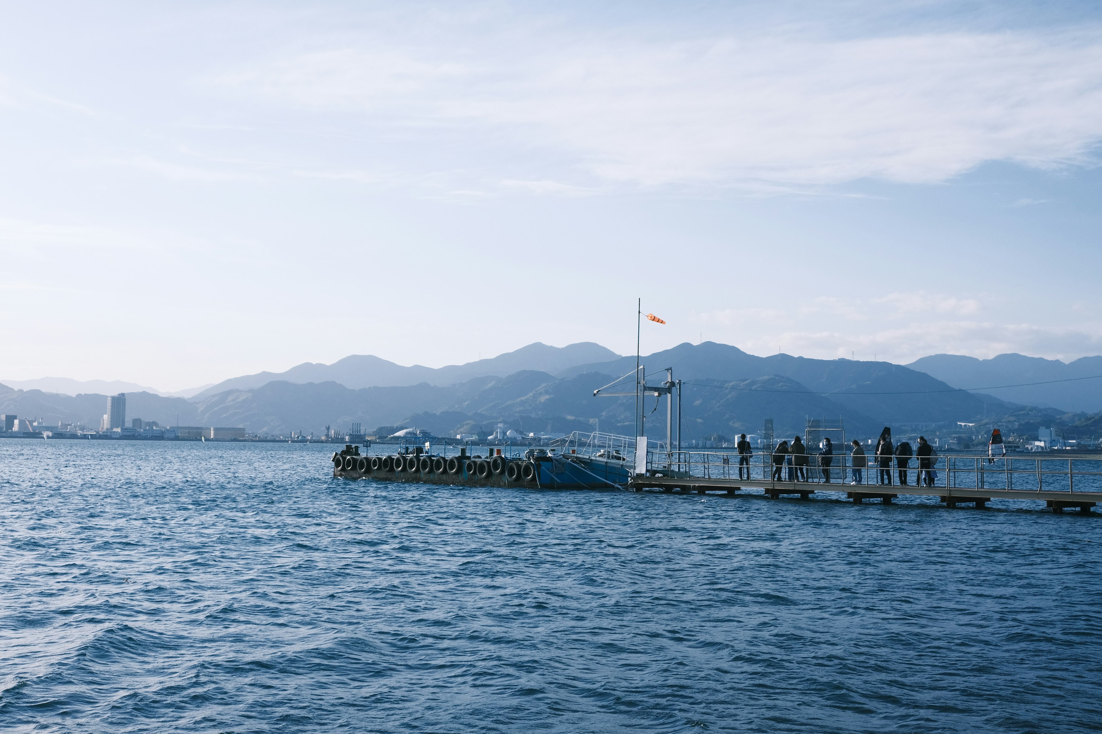 Muelle que se extiende en el agua con montañas al fondo