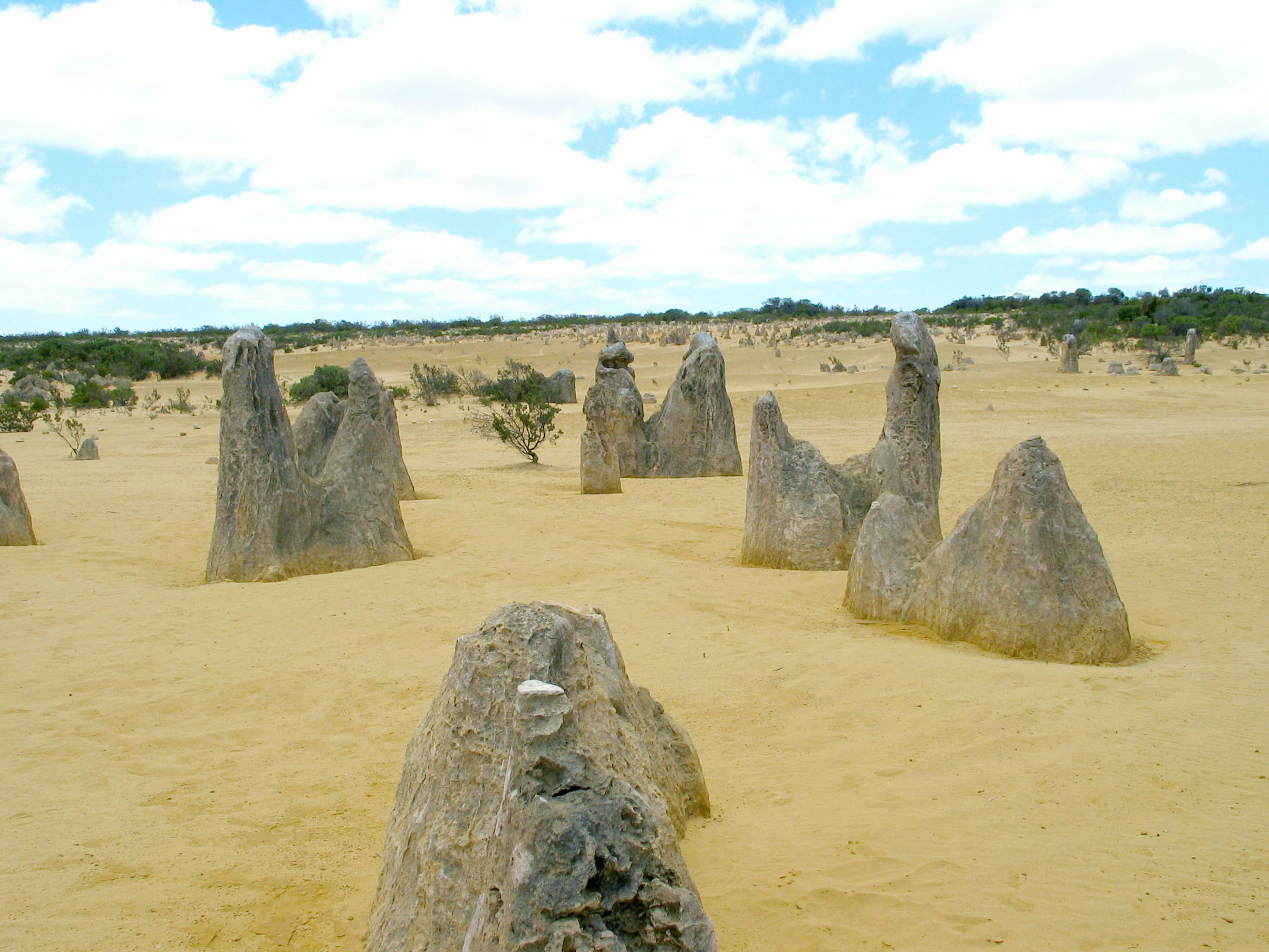 Paisaje de formaciones rocosas únicas en un vasto desierto con cielo azul y nubes blancas